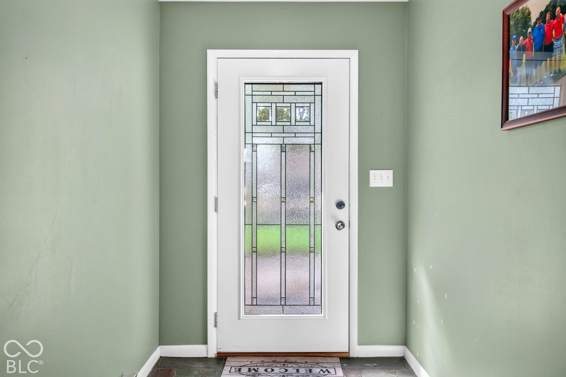 Entry door with decorative glass panels and a white frame