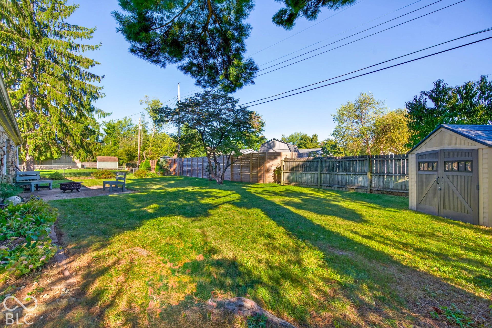 Expansive lawn with mature trees, a privacy fence, and a patio area