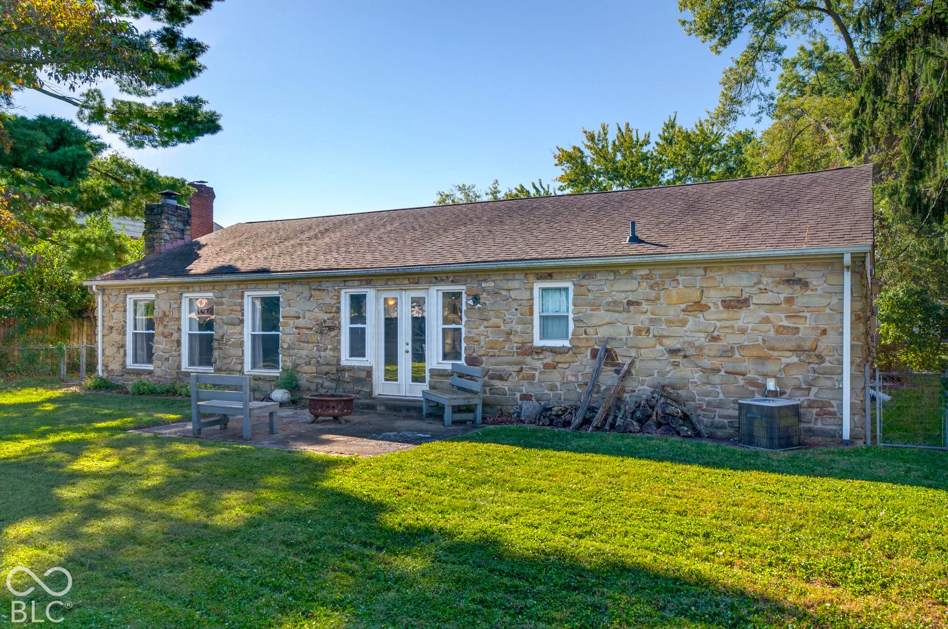 Stone exterior facade with white-framed windows, double glass panel doors, and a shingle roof