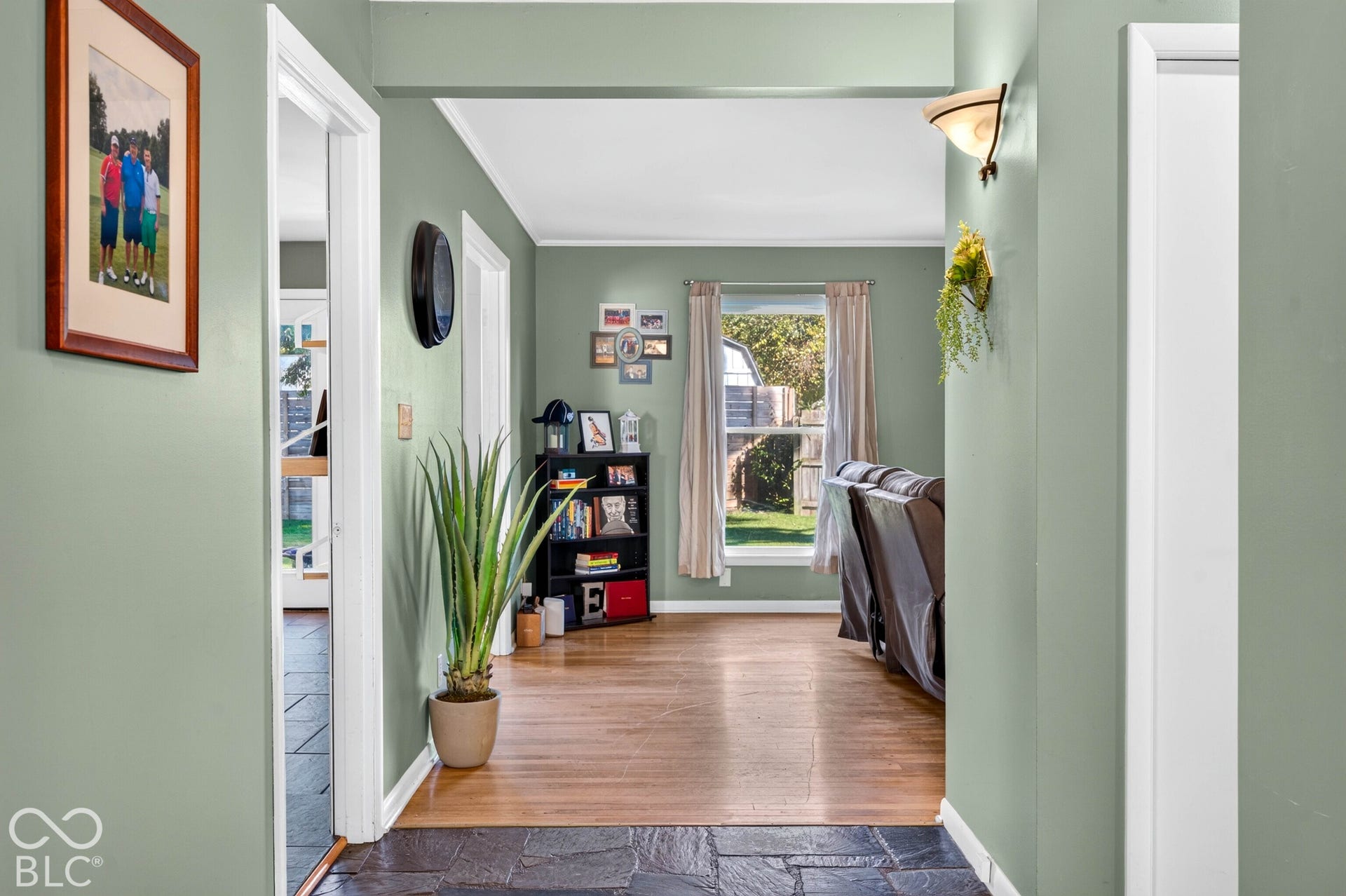 Slate tile flooring, wood-finish flooring, interior architectural archway, wall-mounted light fixture, and a window with exterior views