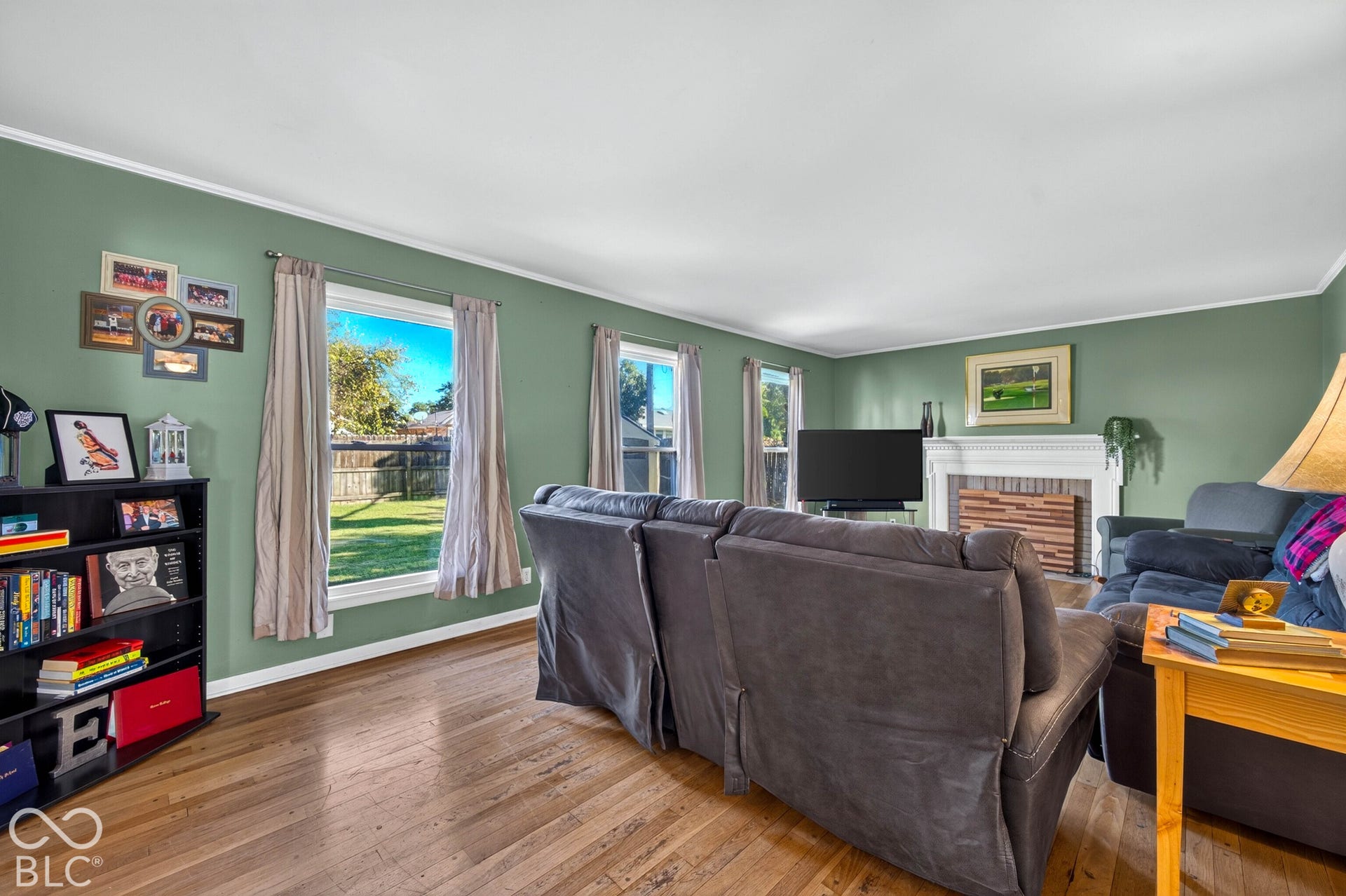 Hardwood flooring, painted walls, white trim, recessed fireplace with decorative screen, built-in shelving