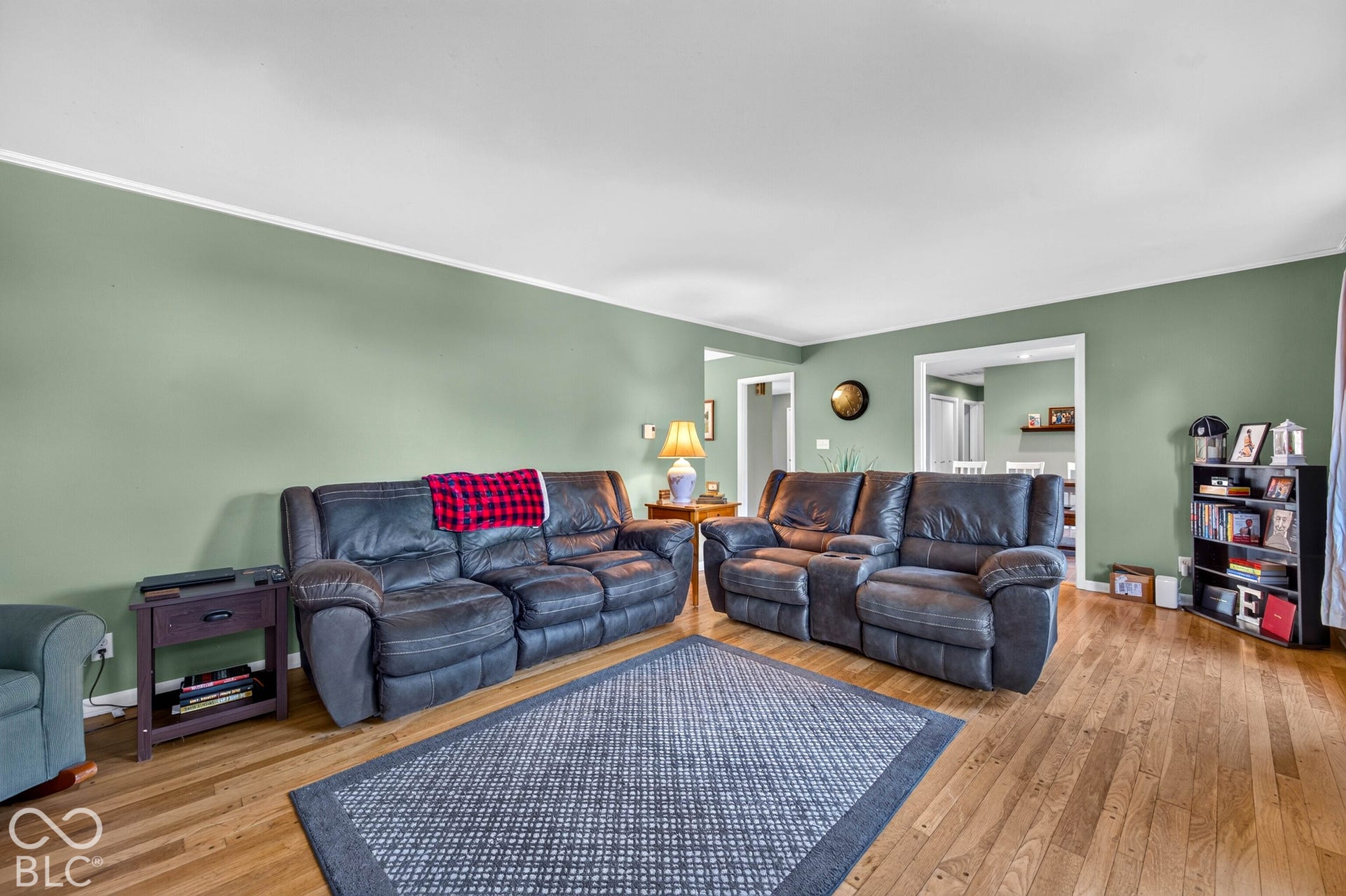 Hardwood flooring, light green painted walls, white trim, and an open doorway