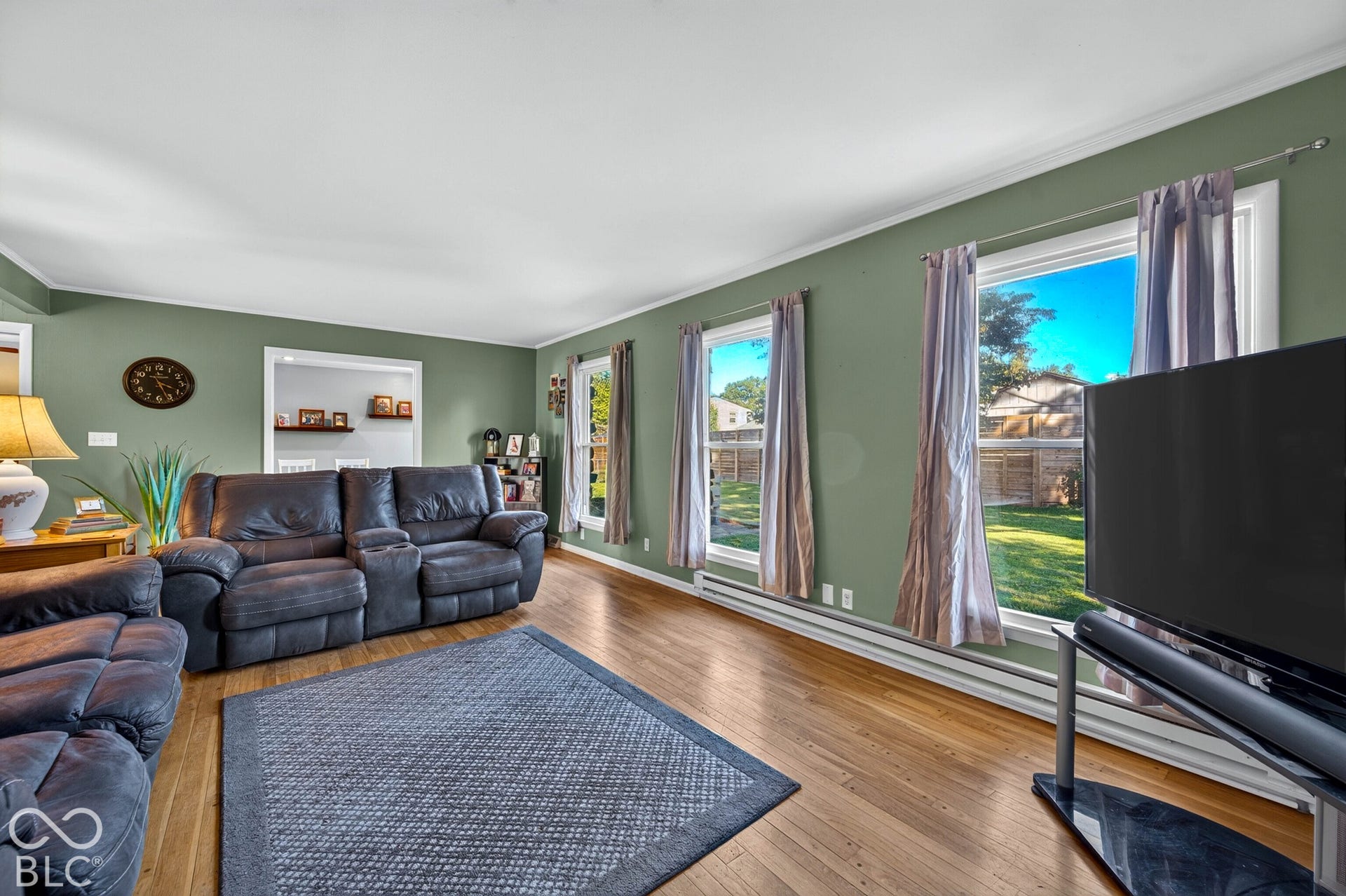 Hardwood flooring, multiple windows, built-in shelving, crown molding, and a neutral wall color