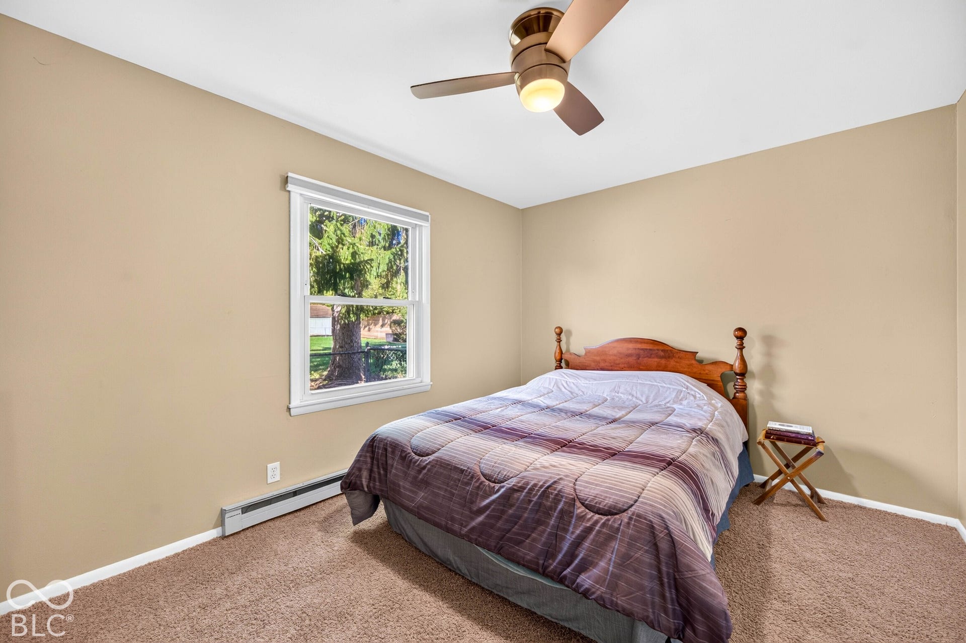 Carpeted flooring, single window with white trim, tan wall paint, ceiling fan with integrated lighting, and a baseboard heater