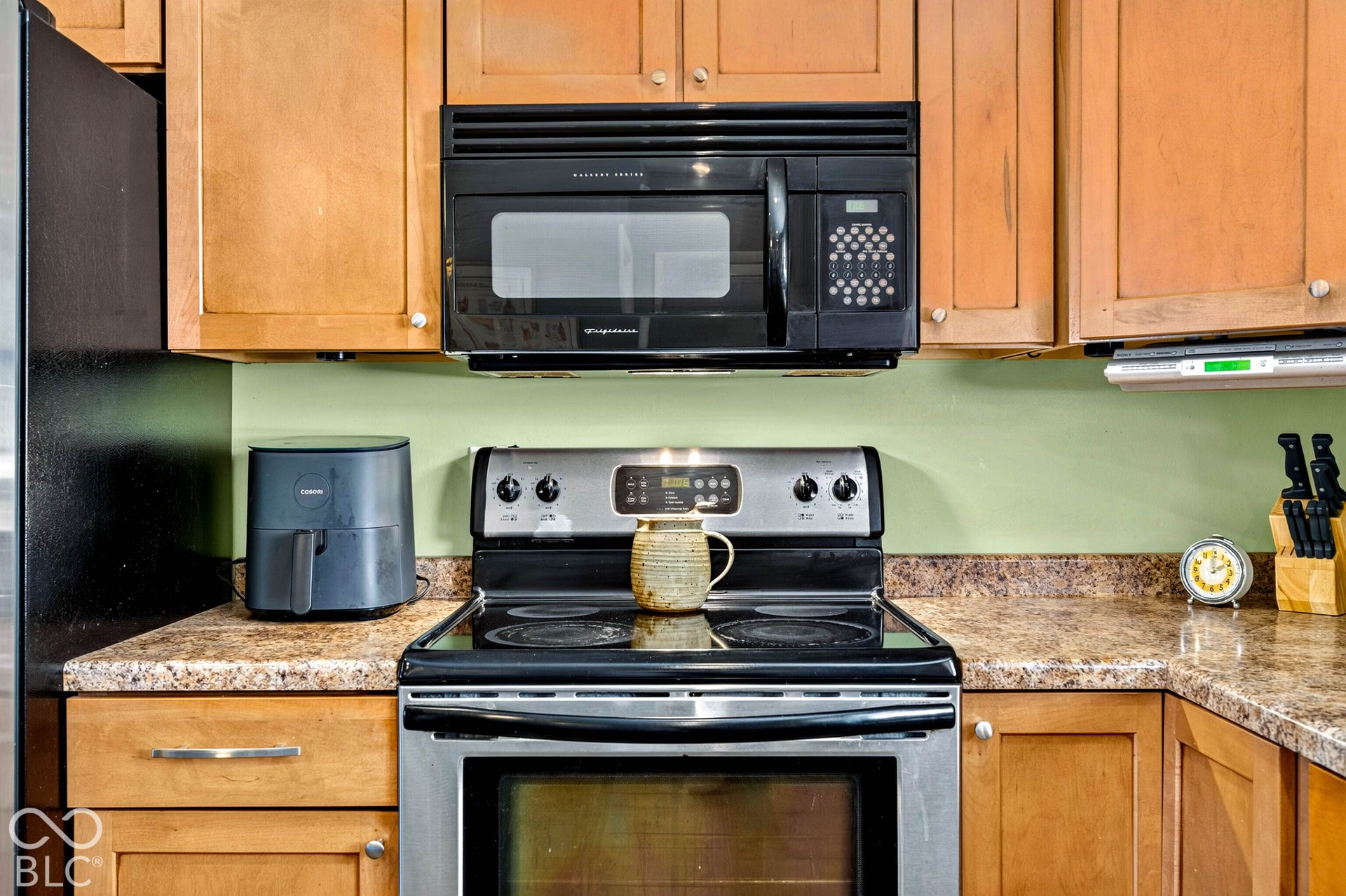 Wood-finish cabinetry with a built-in microwave, stainless steel range, and brown speckled countertops