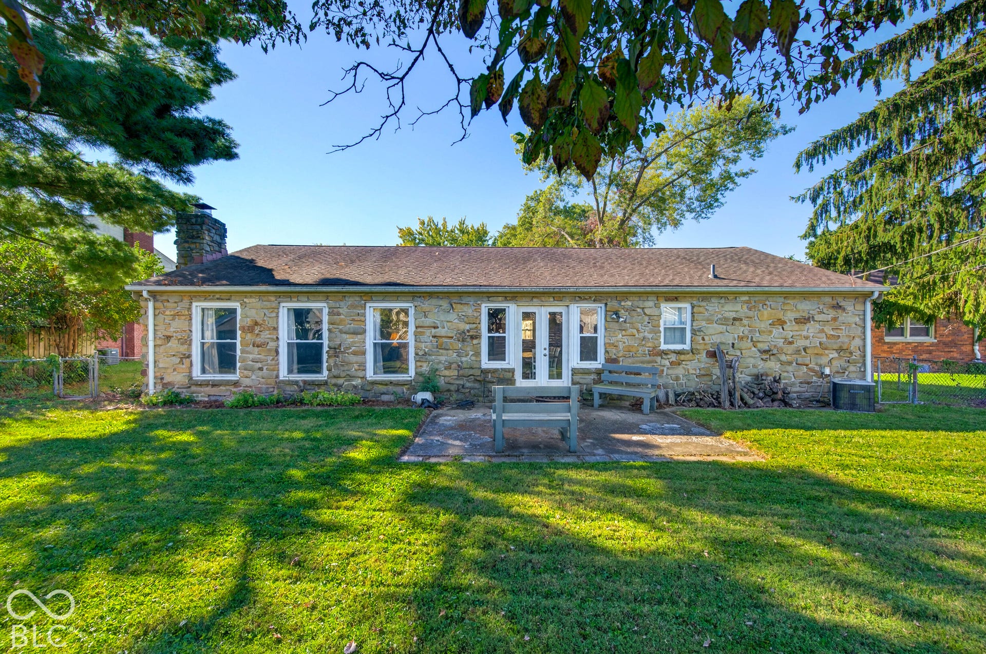 Stone exterior featuring a patio, multiple windows, and a prominent chimney