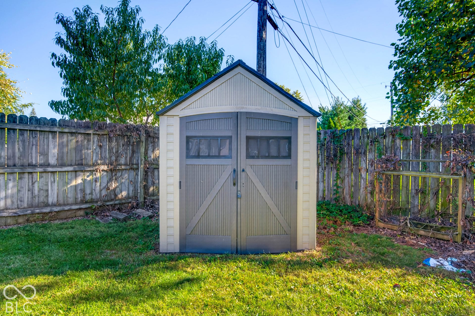 Compact outdoor storage shed with double doors and window accents