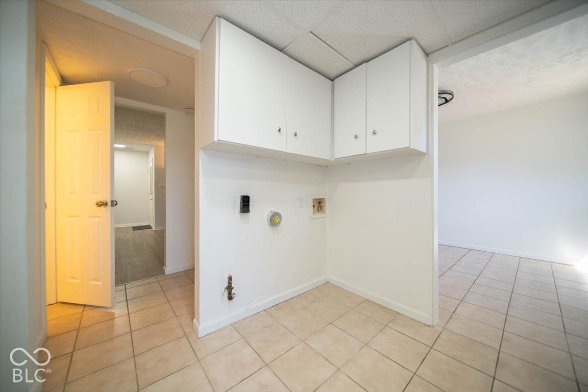 White cabinetry, tile flooring, and utility hookups