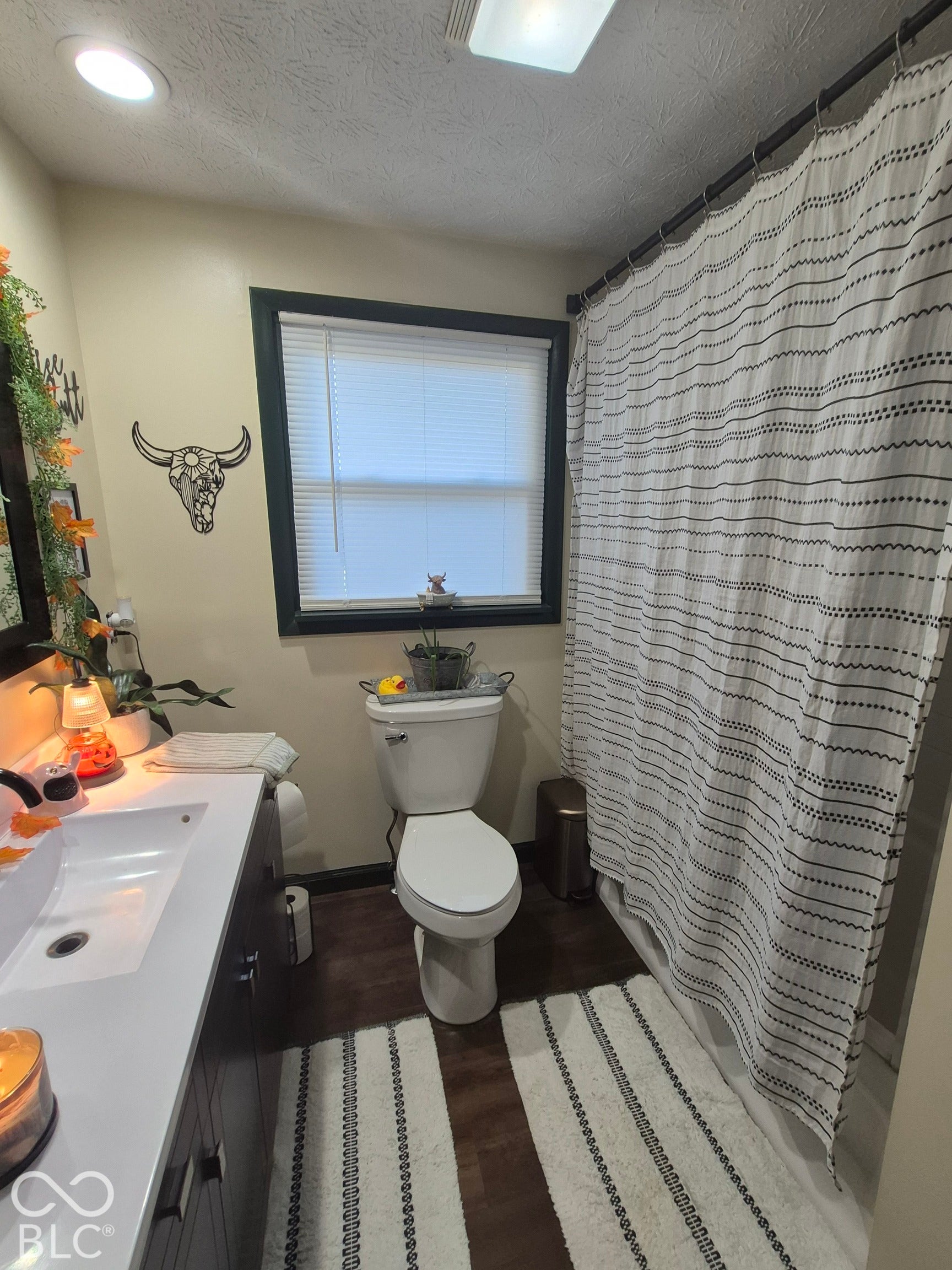 White vanity with an integrated rectangular sink, dark wood-finish cabinetry, and a full-sized mirror