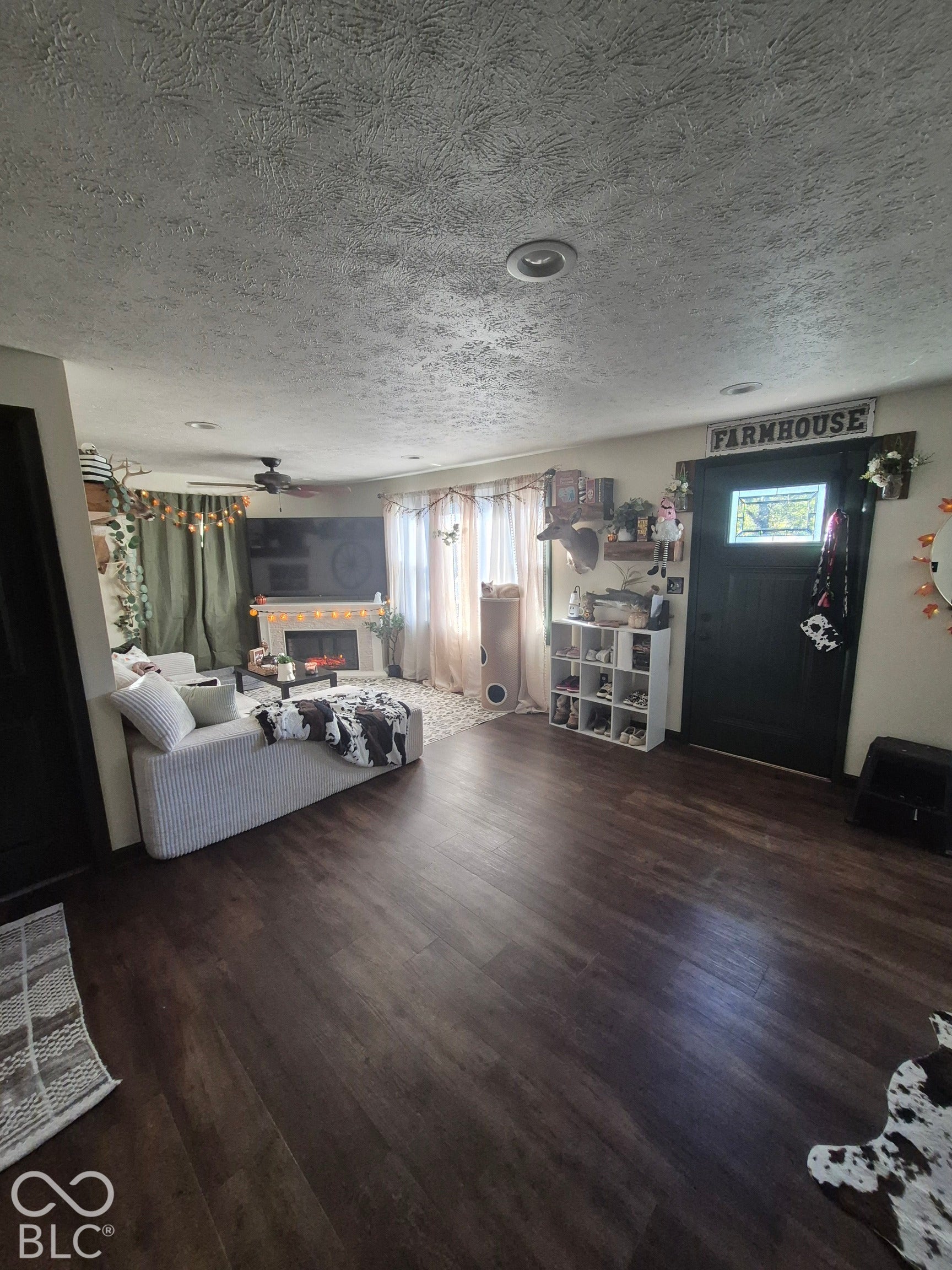 Wood-finish flooring throughout, recessed ceiling lighting, and a dark-paneled front door with a decorative window