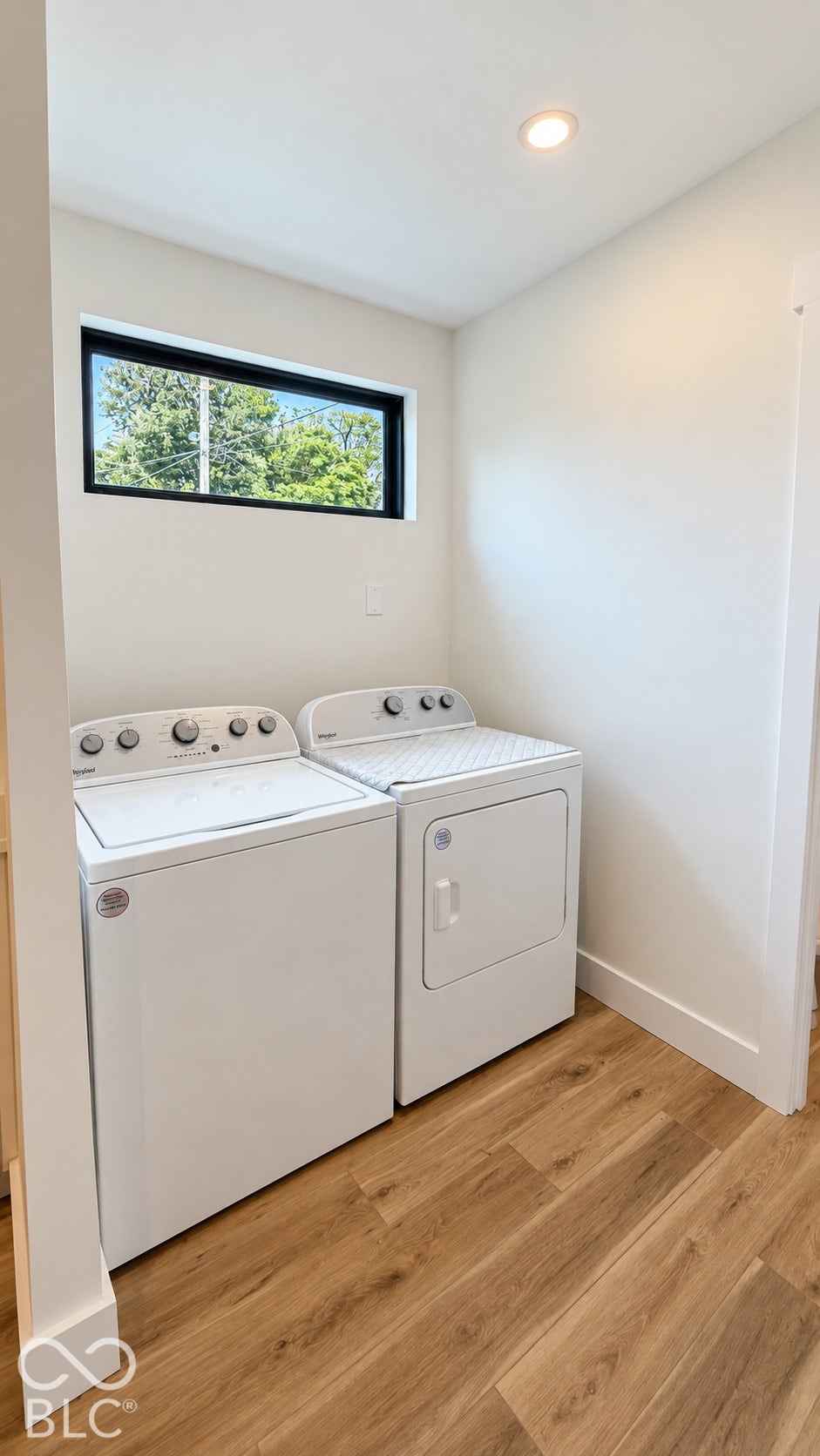 Recessed ceiling lighting, wood-finish flooring, and a rectangular window with dark trim