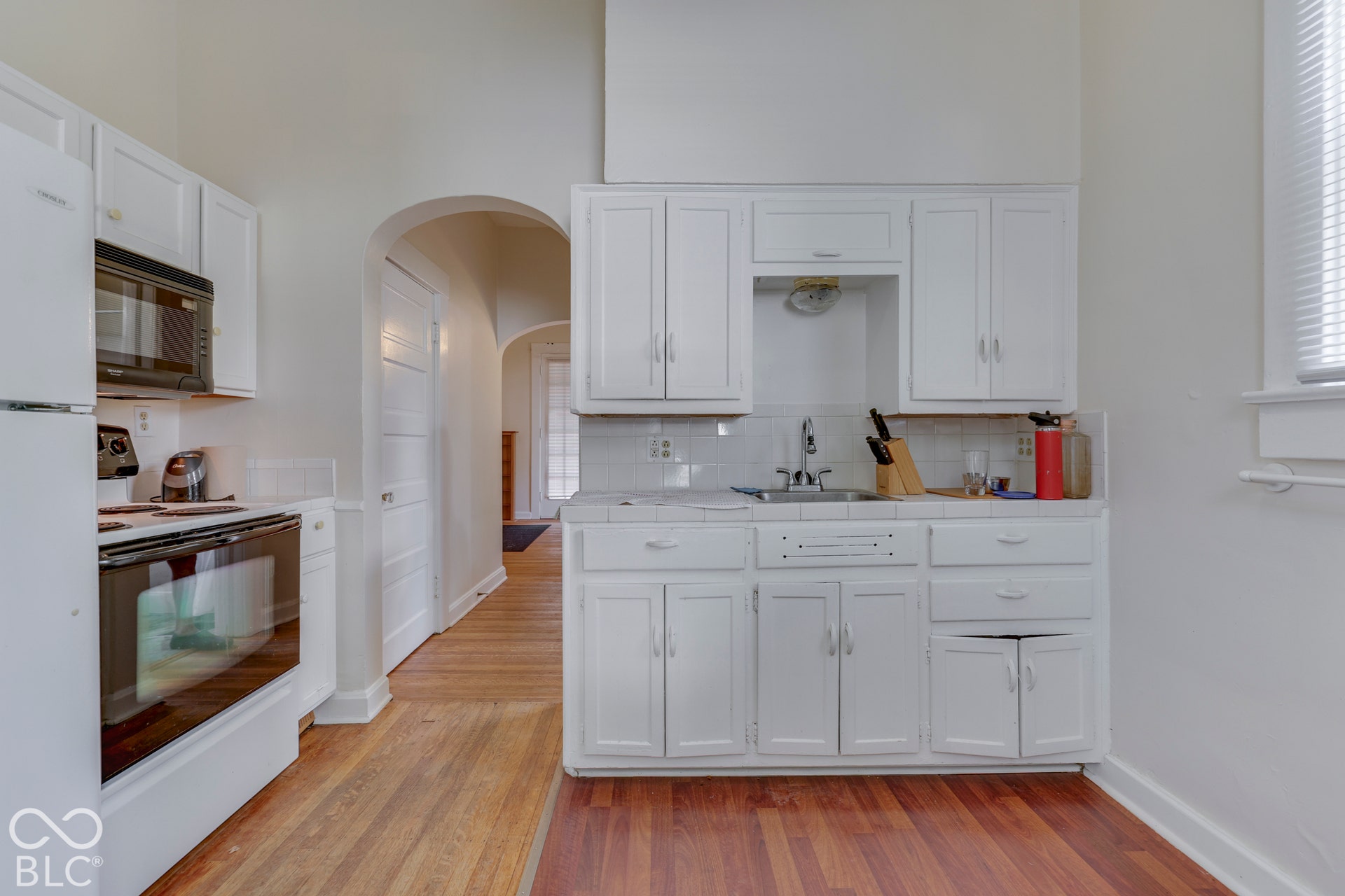 Unit 1White cabinetry, subway tile backsplash, integrated sink, and wood-finish flooring