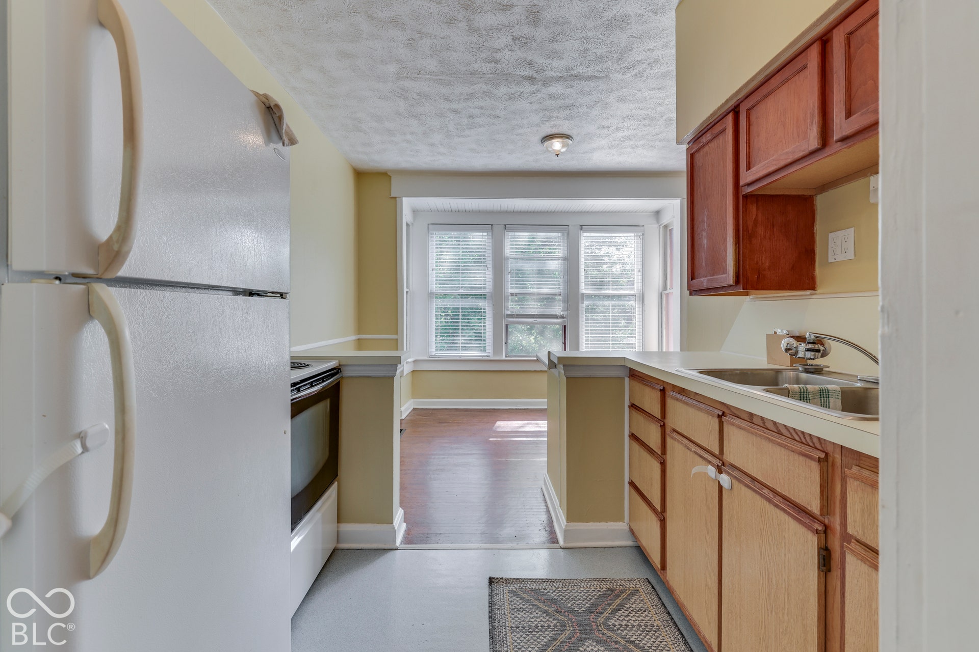Unit 3 Kitchen featuring wood-finish cabinetry, a stainless steel sink, and a white refrigerator