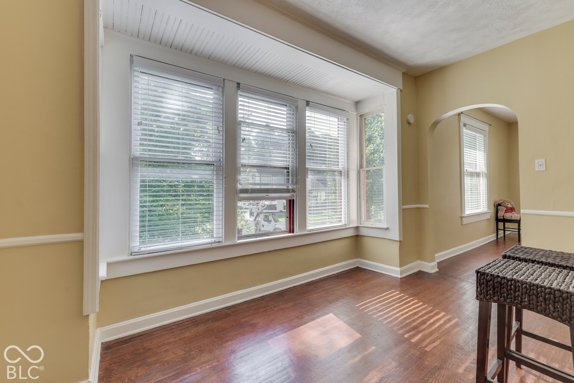 Unit 3 Wood-finish flooring, multiple windows with blinds, arched doorway, and decorative wall molding