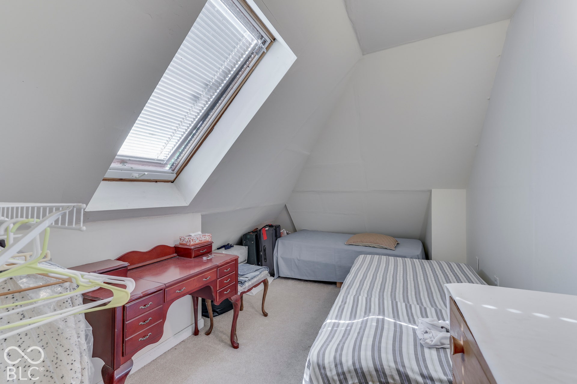 Attic space featuring a sloped ceiling, skylight with blinds, and light-toned carpeting