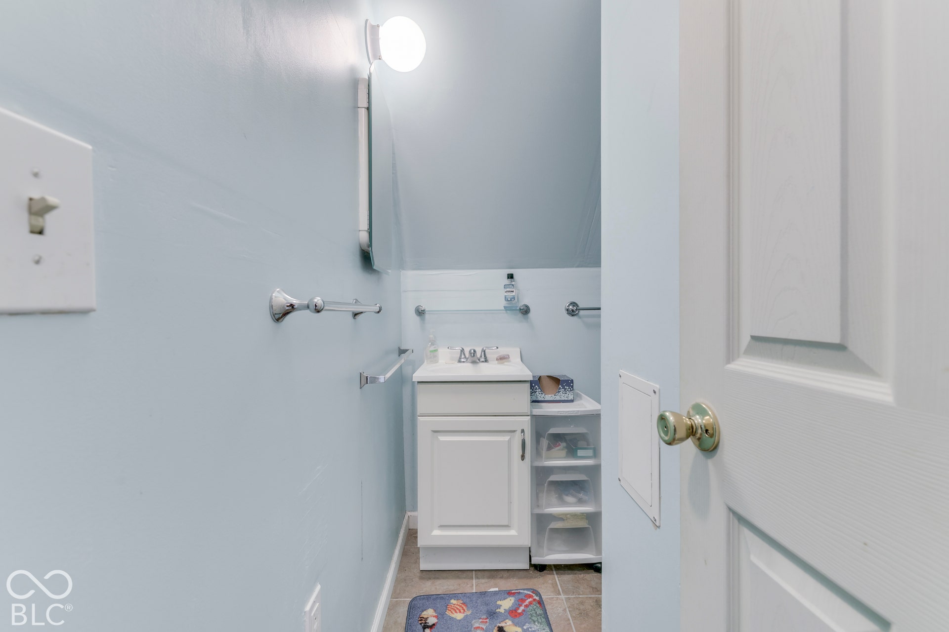 White vanity with a ceramic basin, chrome faucet, and tiled flooring
