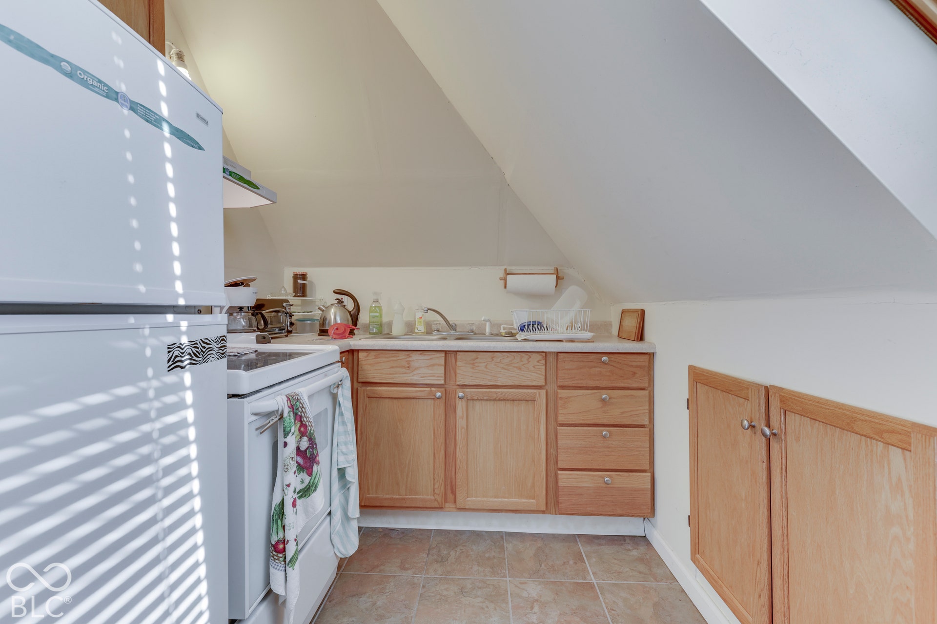 Compact kitchen featuring wood-finish cabinetry, a white electric range, and a refrigerator