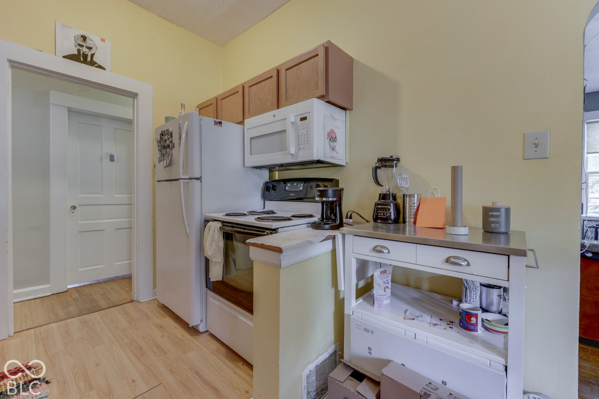 Unit 2 Wood-finish flooring, overhead cabinetry, and white appliances, including a range, refrigerator, and microwave