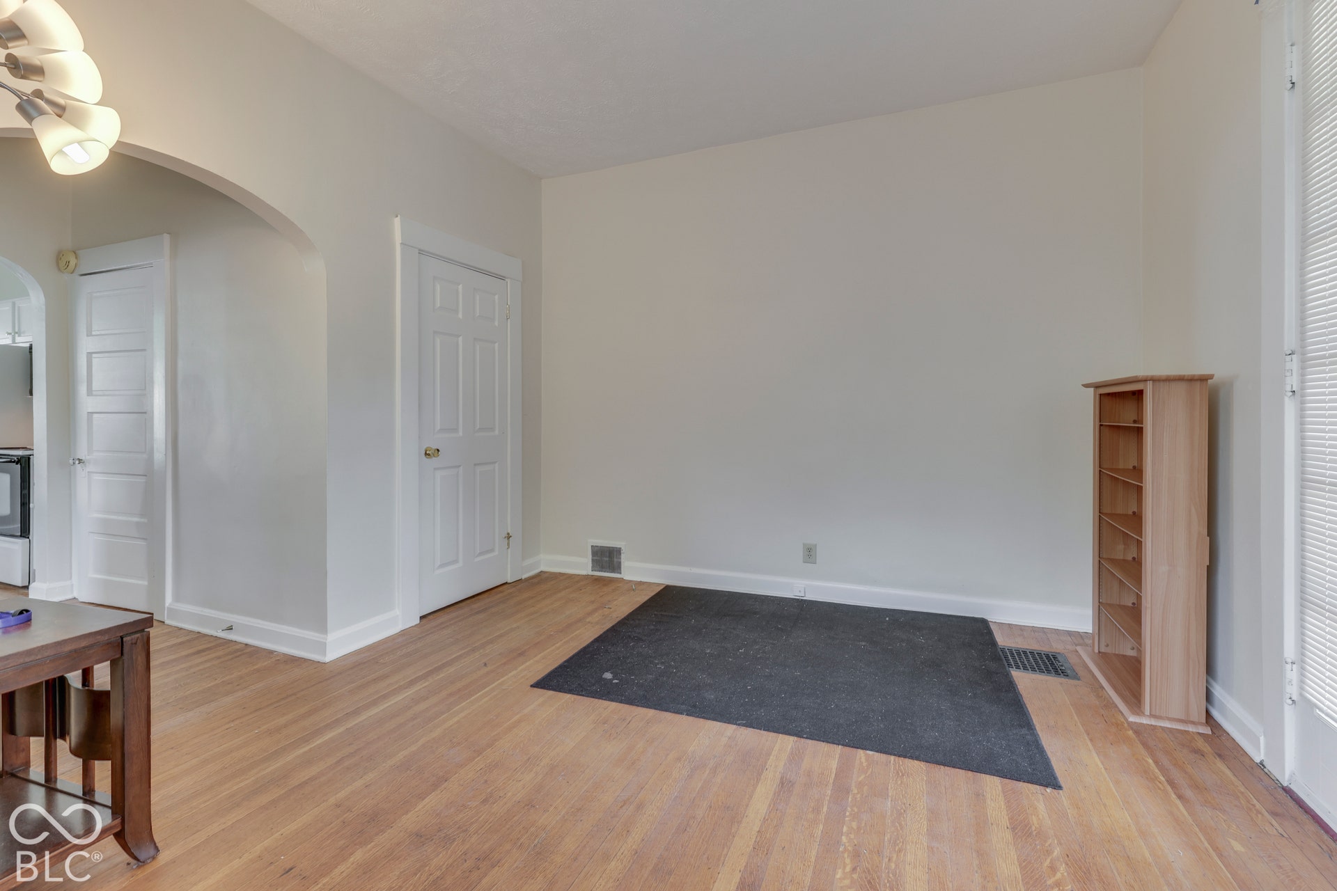 Unit 1 Wood-finish flooring, white trim work, neutral wall paint, and an arched doorway
