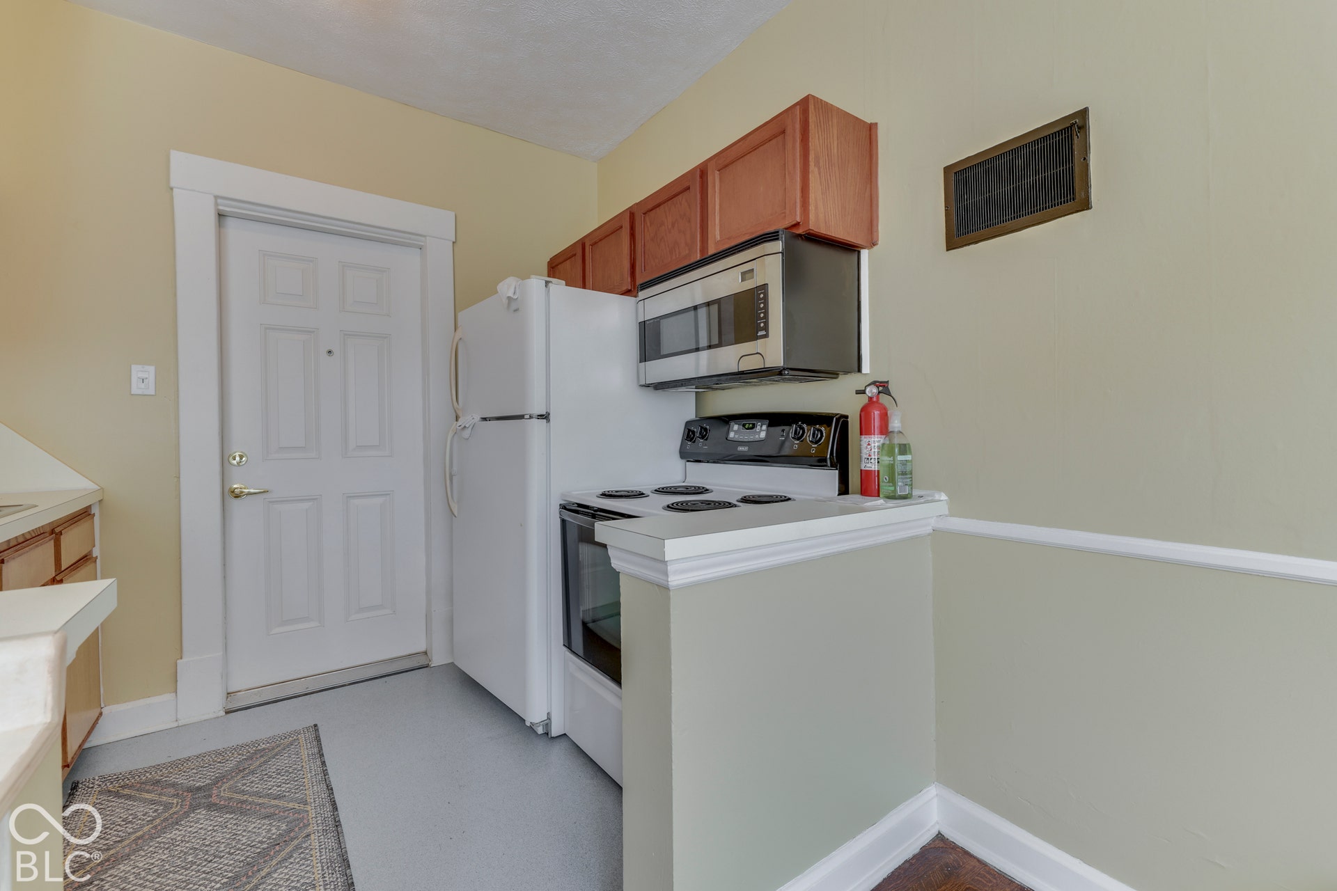 Unit 3 Kitchen area featuring a white four-panel entry door, white refrigerator, and stainless steel microwave