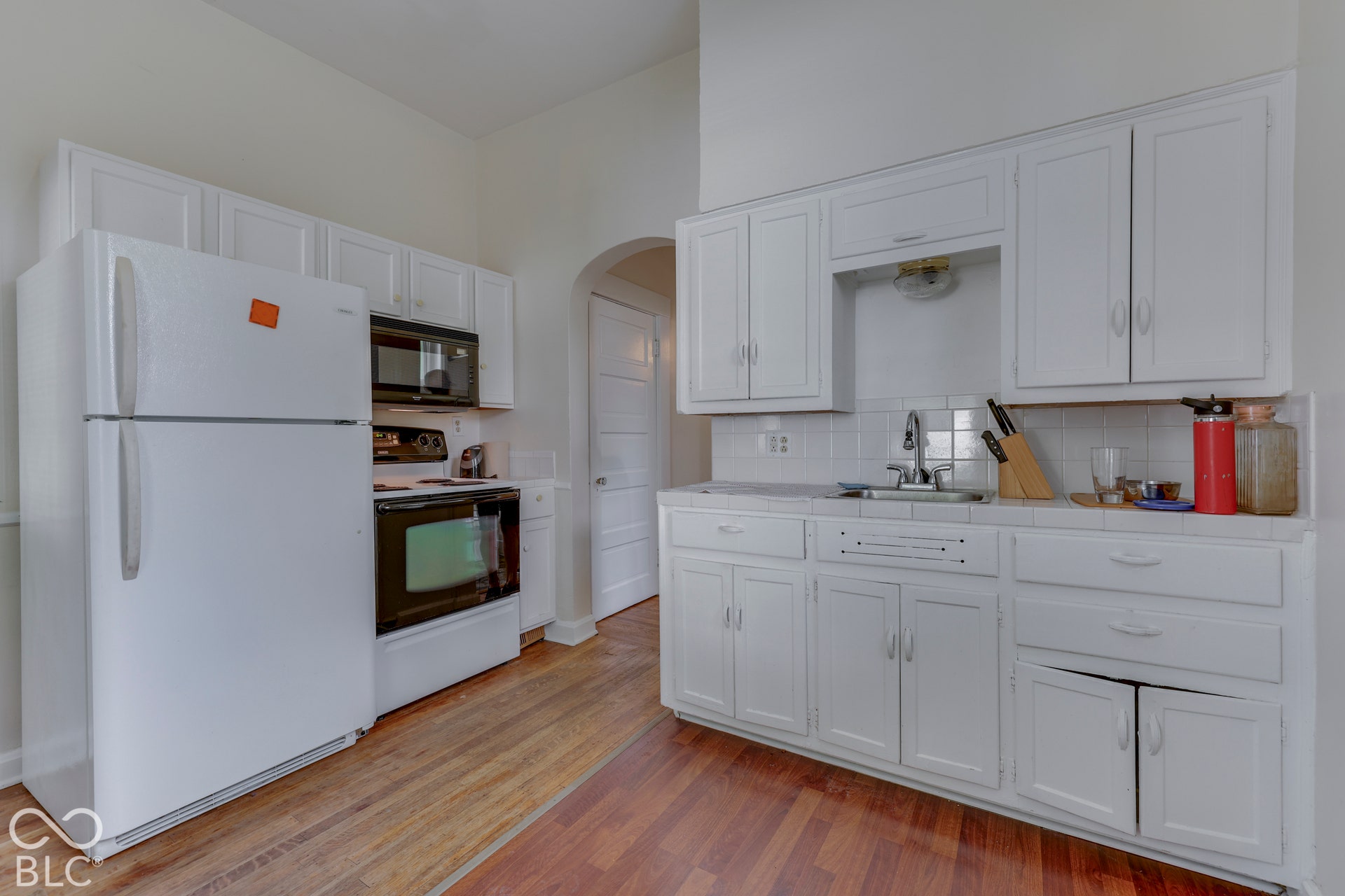 Unit 1 Kitchen with white cabinetry, wood-finish flooring, and white subway tile backsplash