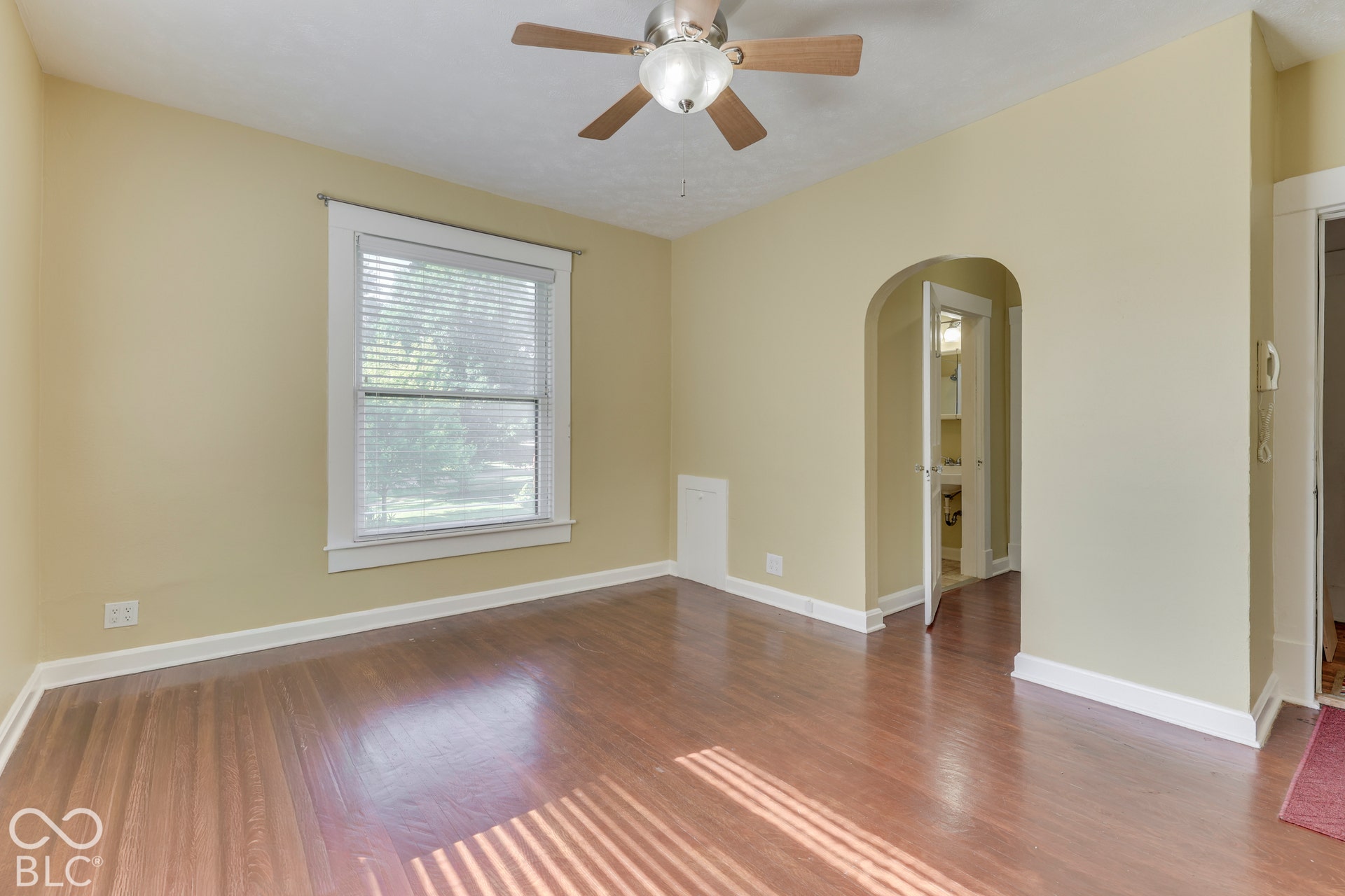 Unit 3 Hardwood flooring, arched doorway, window with blinds, ceiling fan with light, and white trim