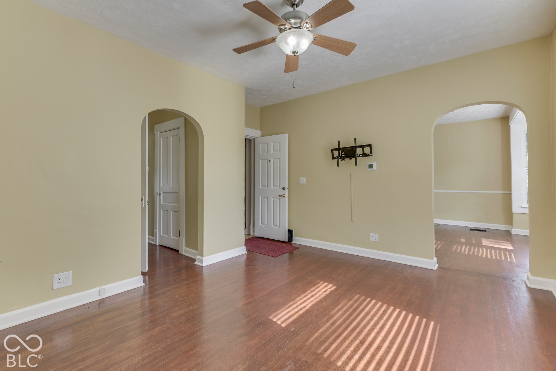 Unit 3 Wood-finish flooring with arched doorways, ceiling fan, and white trim