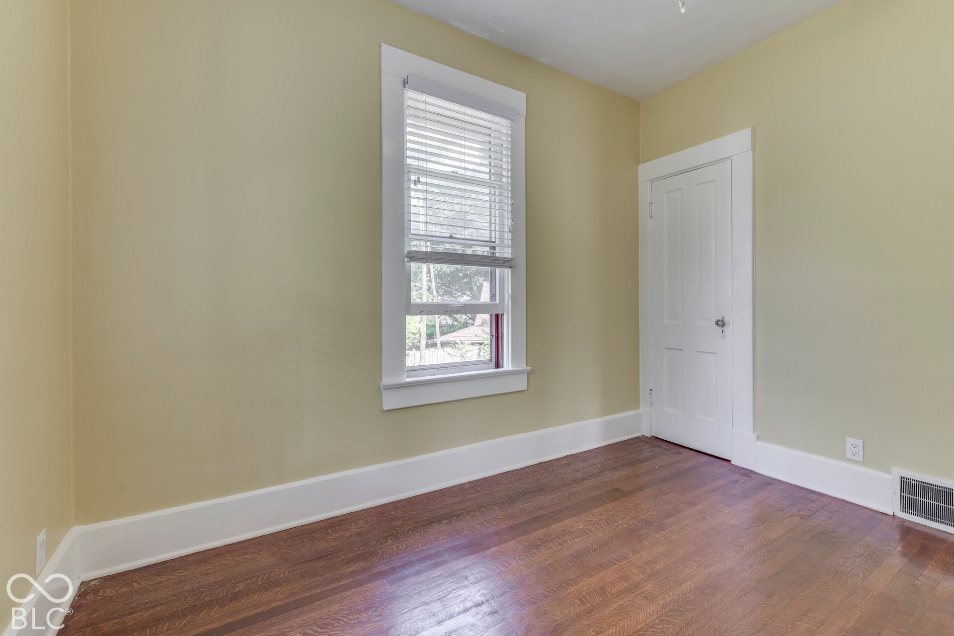 Unit 3 Hardwood flooring, painted walls, white trim, a single window with blinds, and a paneled interior door