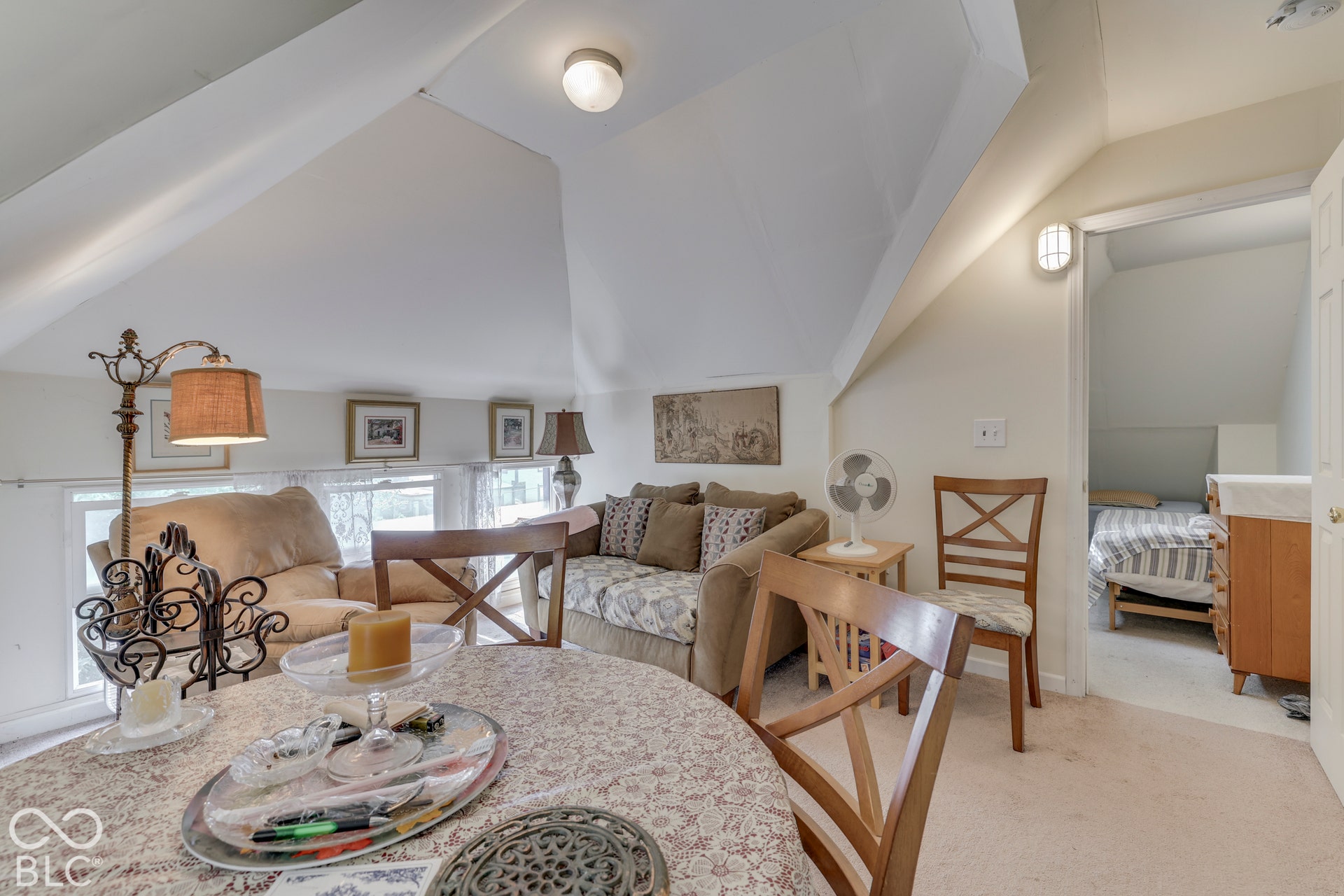Carpeted attic space with a sloped ceiling and flush mount lighting