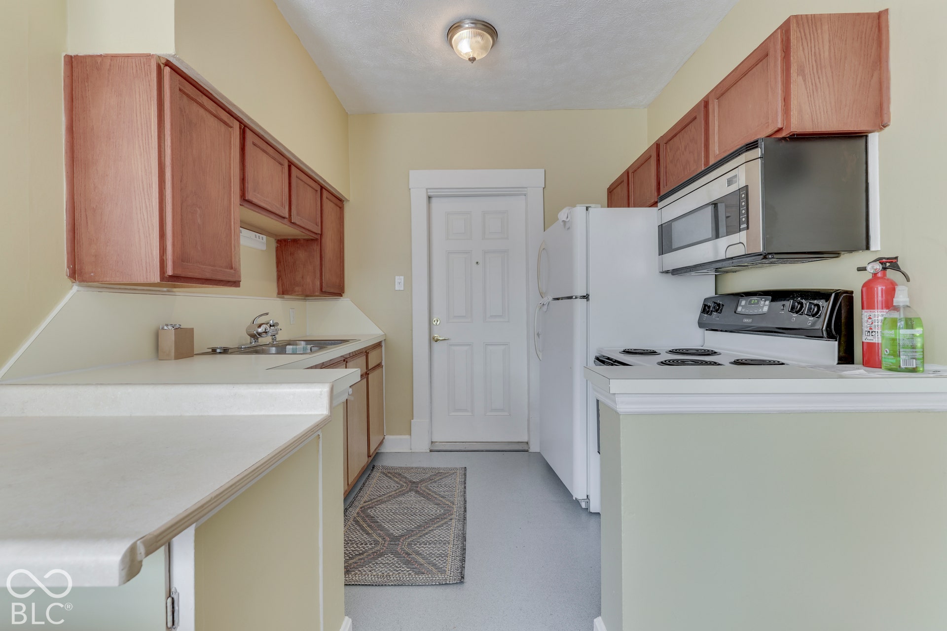 Unit 3 Kitchen featuring wood cabinetry, white countertops, a stainless steel sink, a built-in microwave, and a white refrigerator