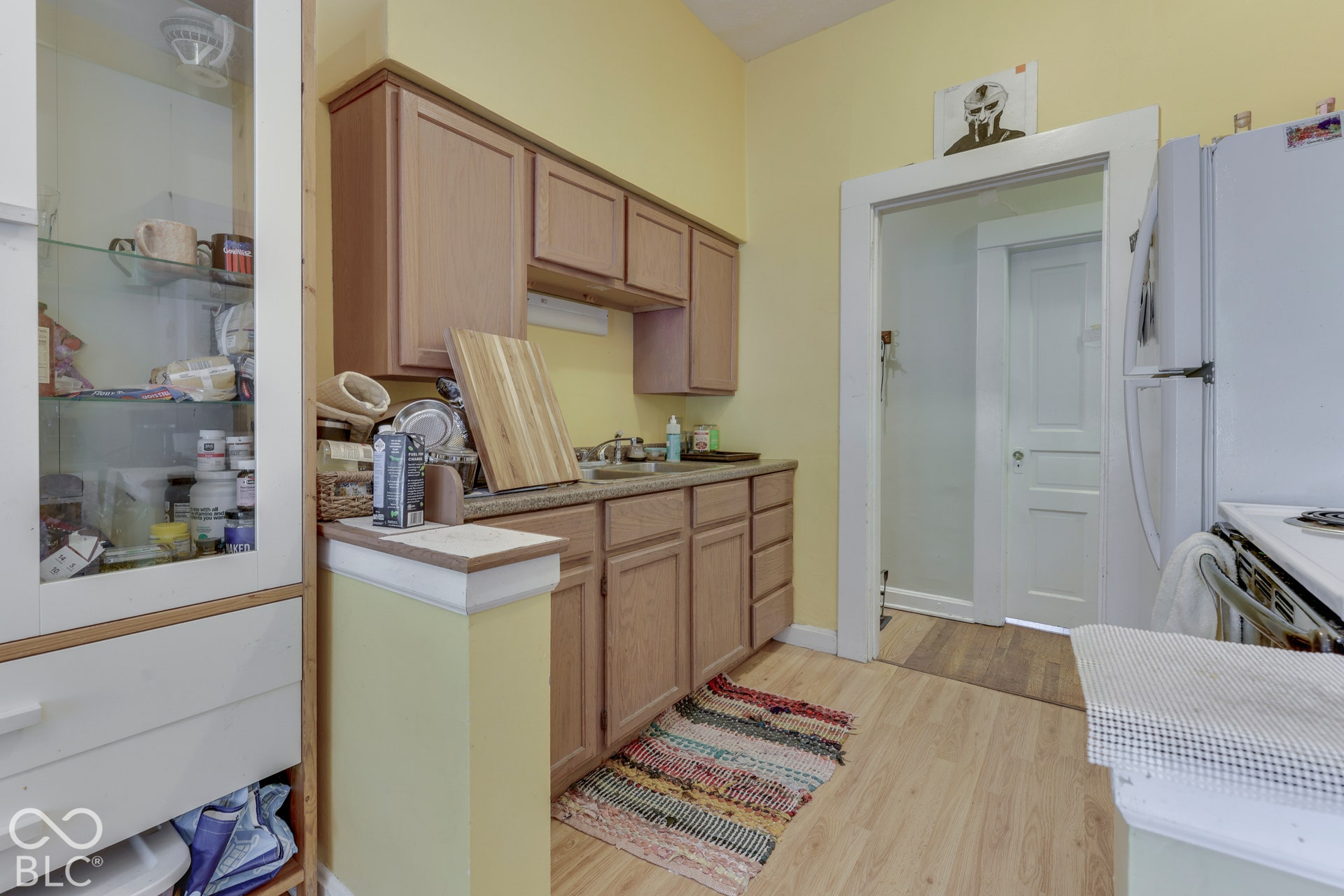 Unit 2 Wood-finish flooring with light-toned cabinetry, a stainless steel sink, and a built-in display cabinet
