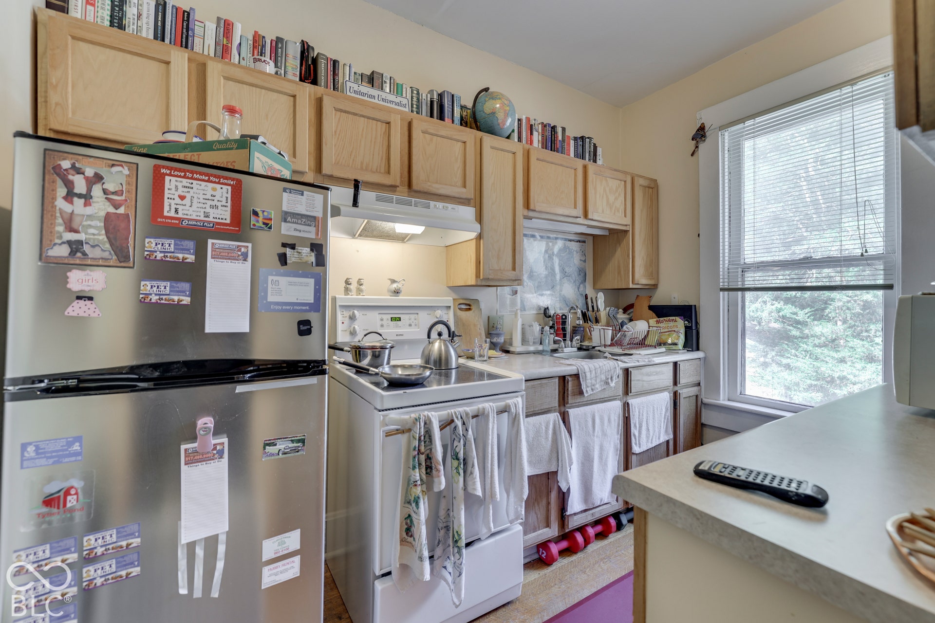 Unit 4 Kitchen featuring light wood-finish cabinetry, a stainless steel refrigerator, white appliances, and a window with blinds