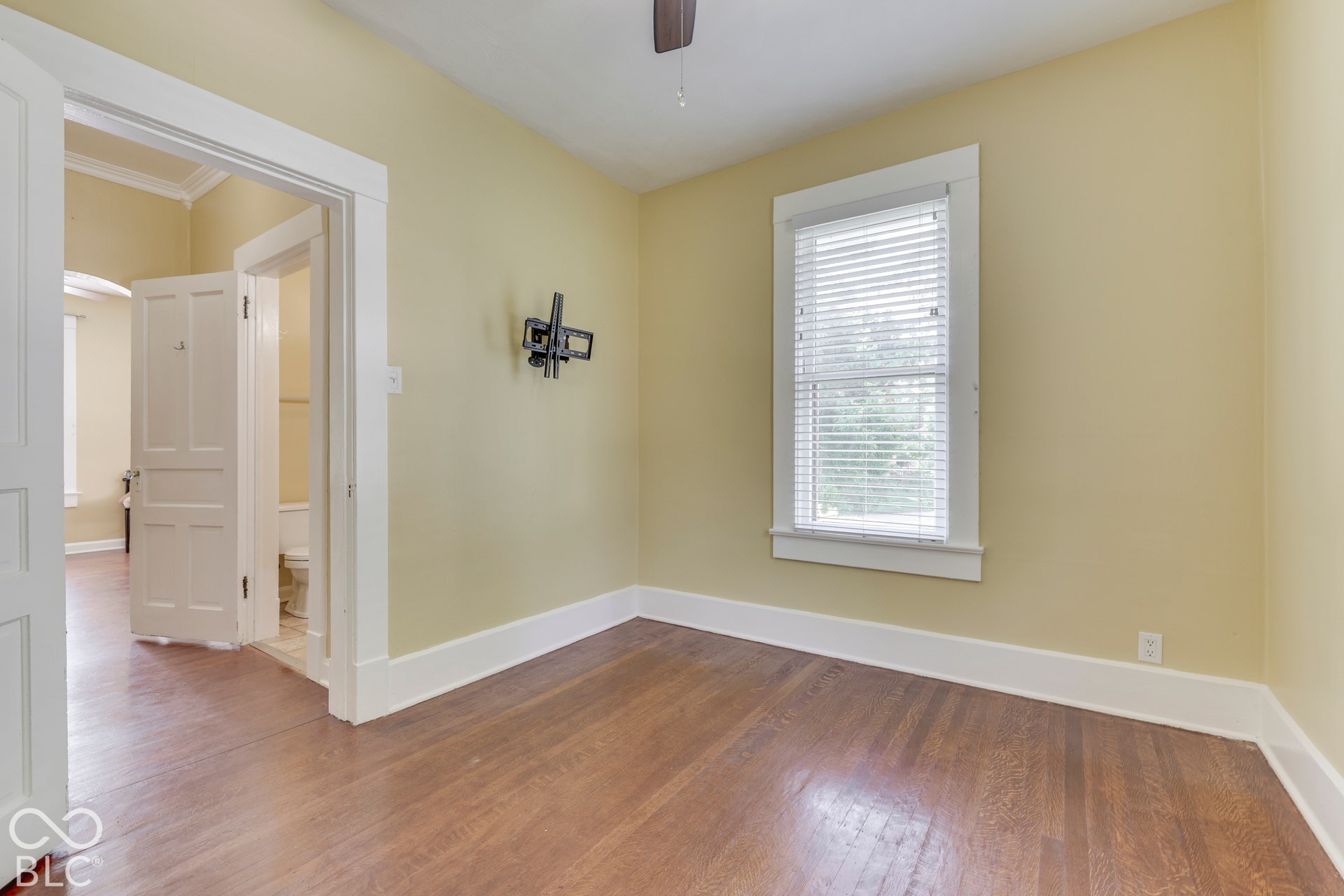 Unit 3 Wood-finish flooring, single window with blinds, light-toned wall paint, white trim, and a ceiling fan