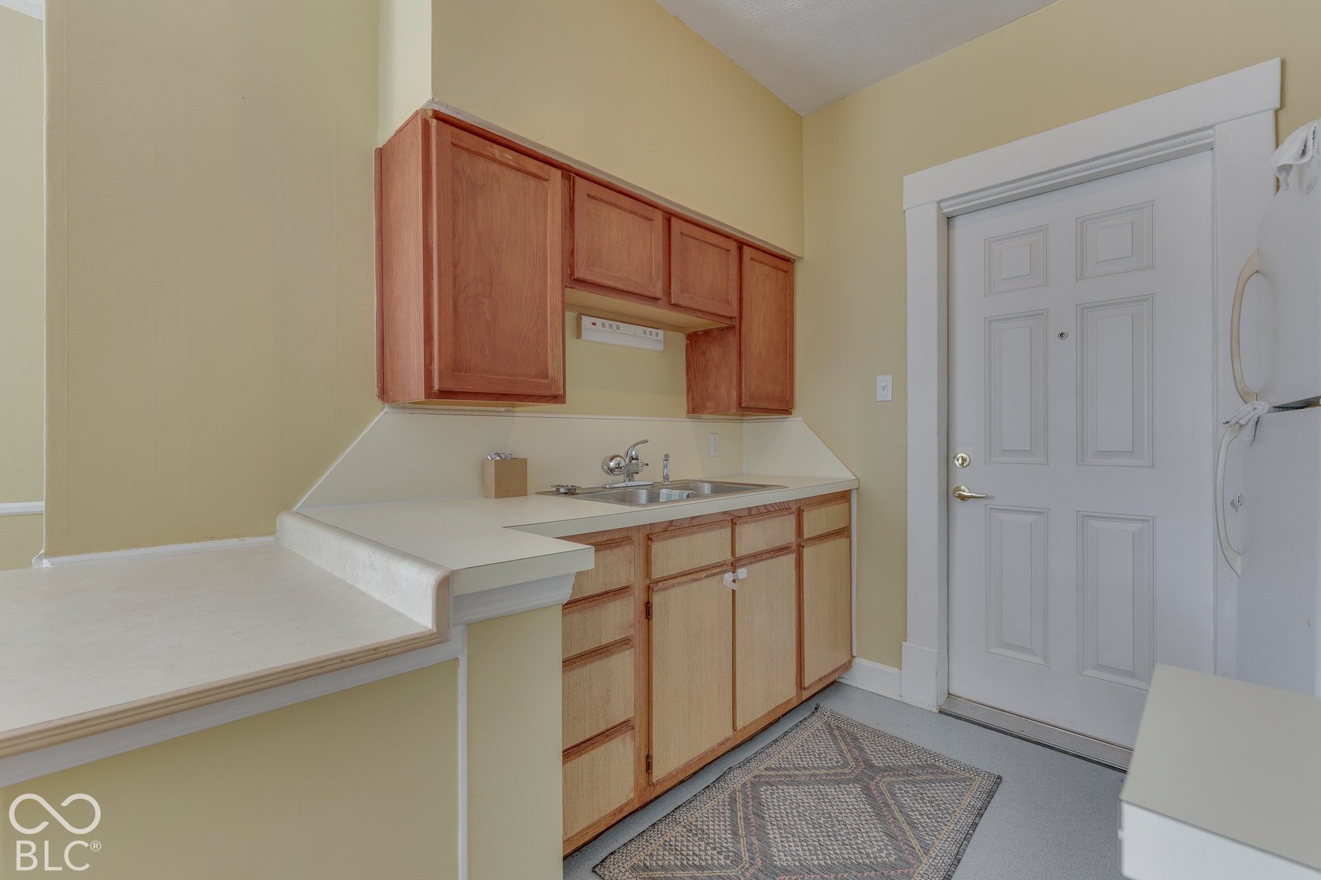 Unit 3 Kitchenette with wood-finish cabinetry, light-toned countertops, and a double-basin sink