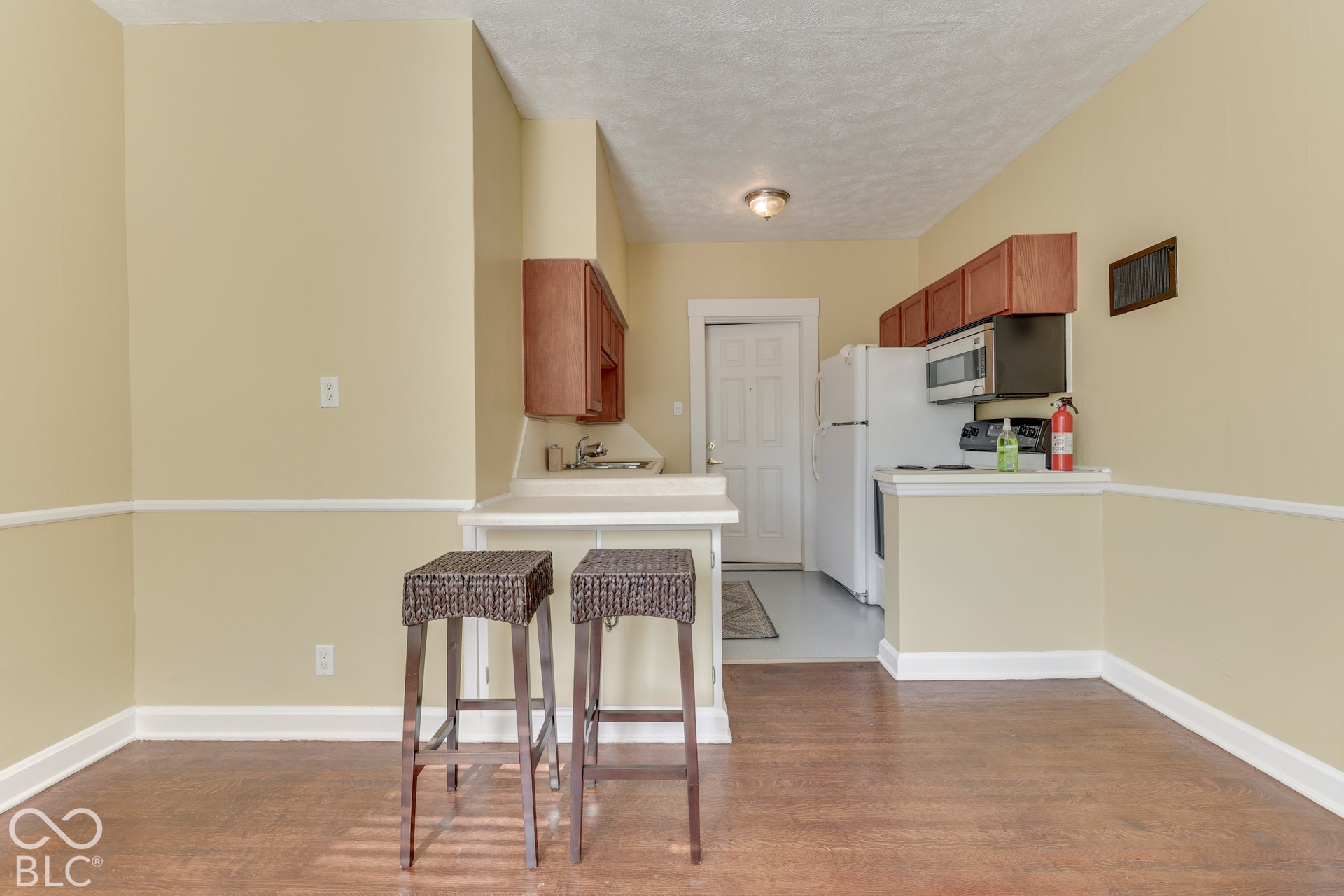 Unit 3: Efficient kitchen space featuring wood-finish cabinetry, a stainless steel microwave, and a built-in breakfast bar