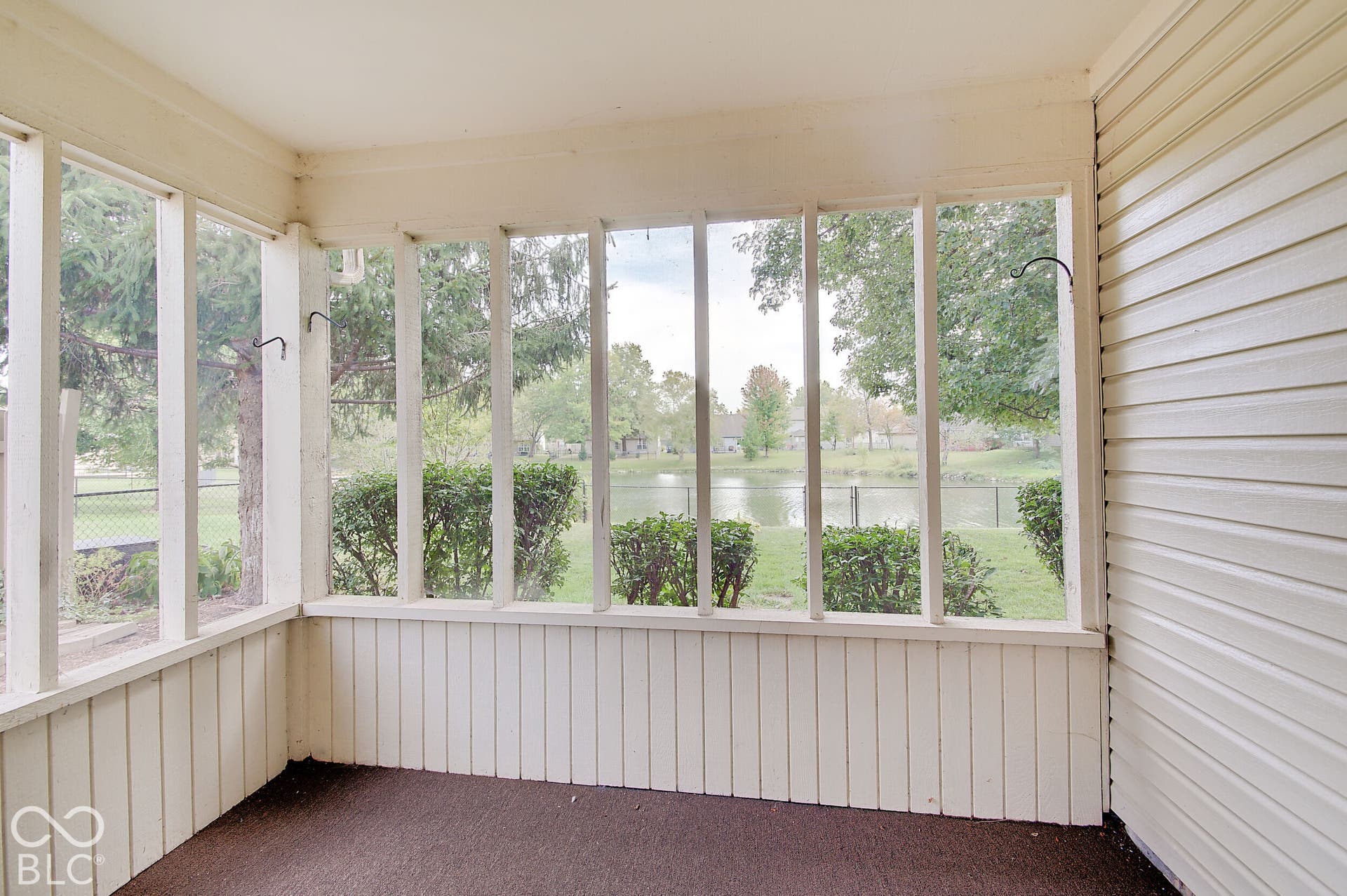 Screened porch with white paneling and a lake backdrop