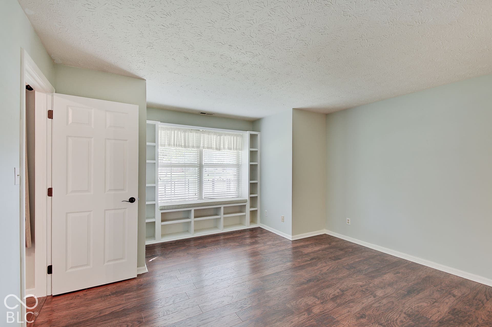 Built-in shelving with window seating, wood-finish flooring, and light-toned walls