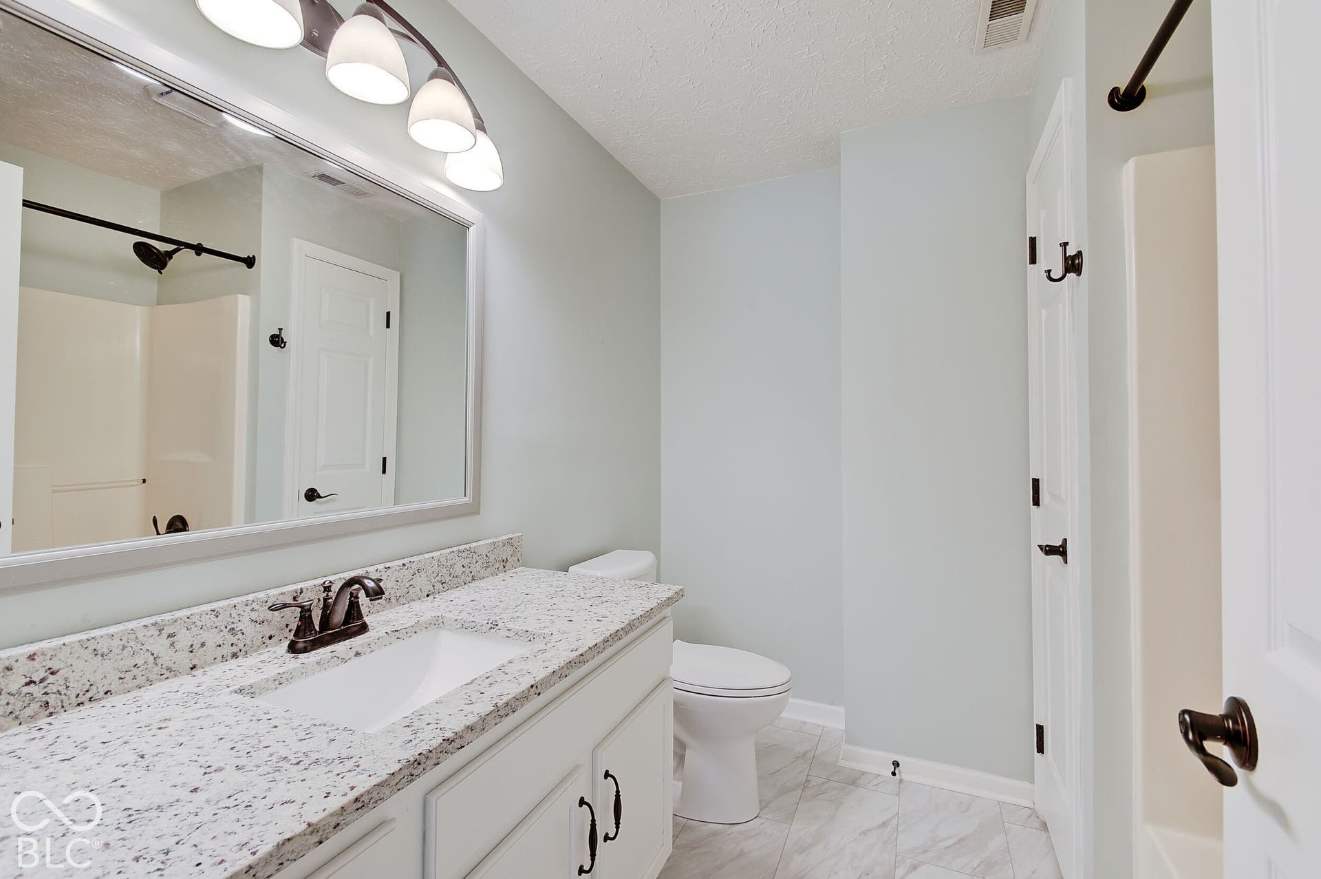 Vanity with integrated sink, speckled countertop, and bronze-finish faucet