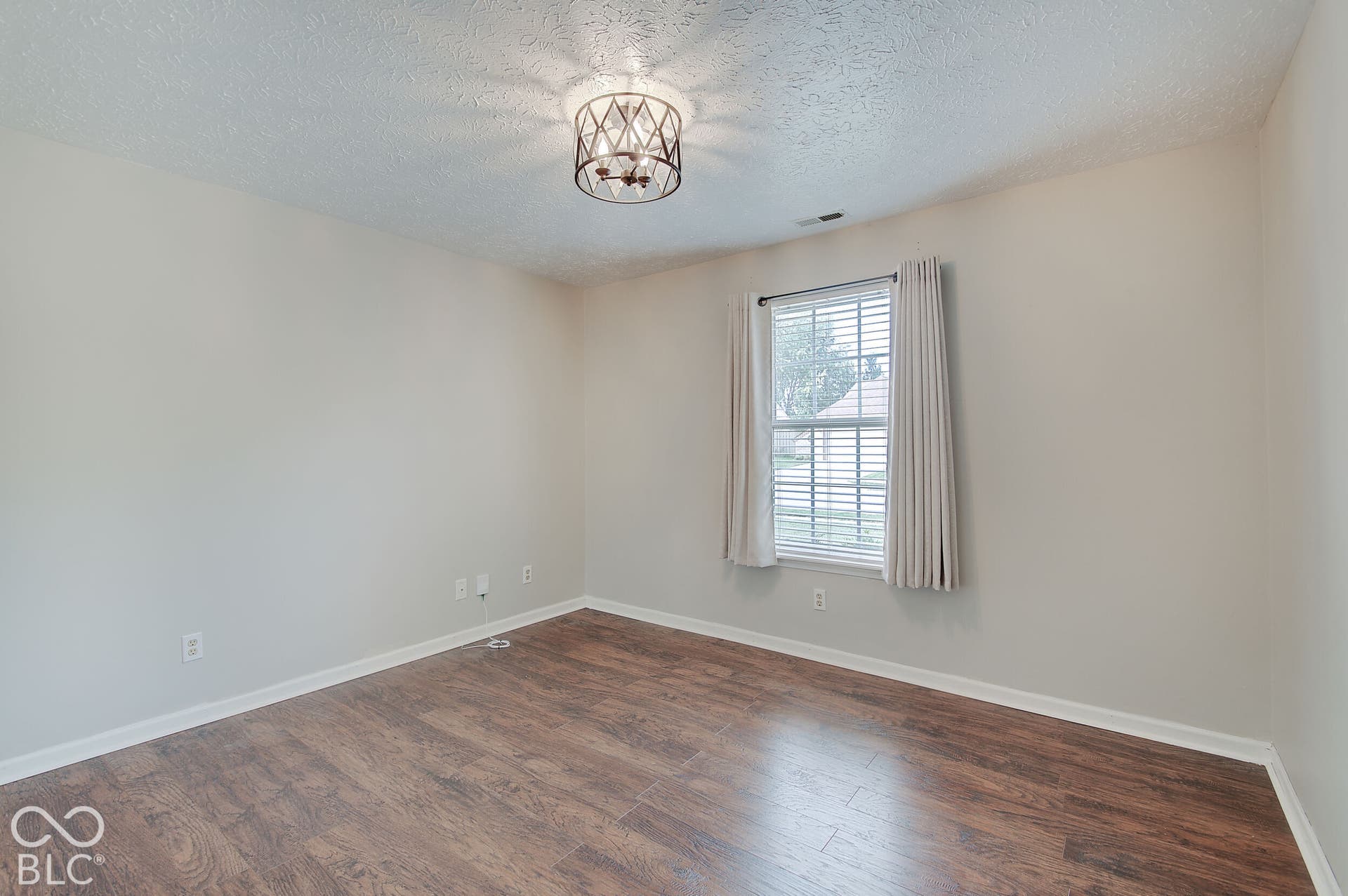 Wood-finish flooring, single window with blinds, ceiling-mounted light fixture, and neutral wall paint