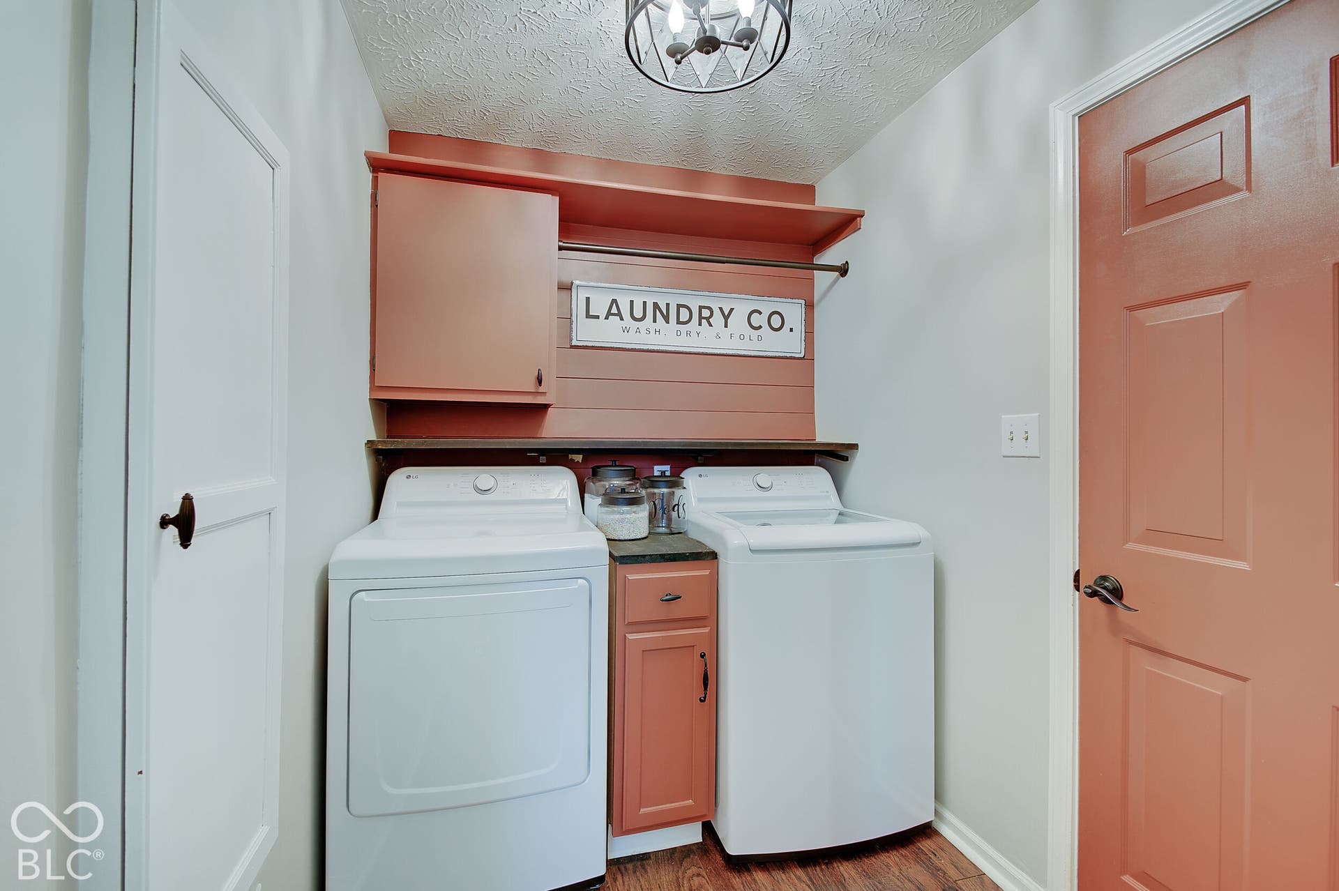 Laundry area with wood-finish flooring, built-in cabinetry, and a ceiling-mounted light fixture