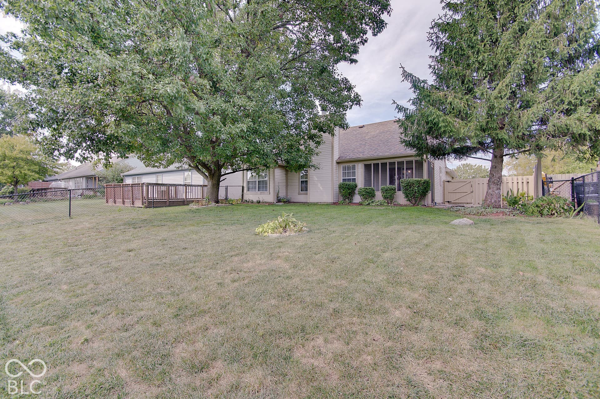 Expansive grounds featuring mature shade trees and a generous lawn area, with a brick residence and detached outbuildings visible across the property