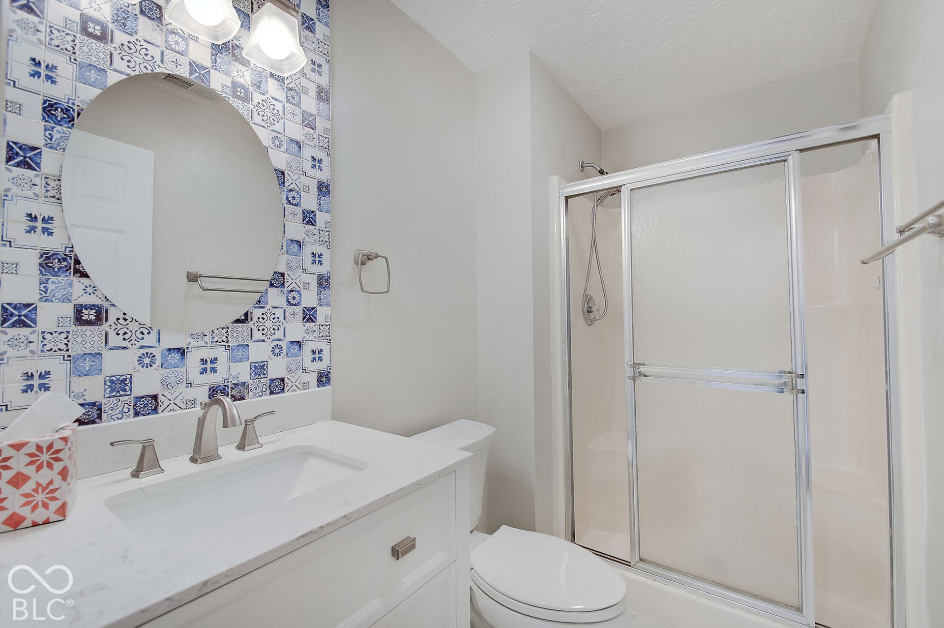 Modern bathroom featuring a white quartz countertop with dual sink vanity, polished nickel fixtures, and ample mirror with integrated lighting