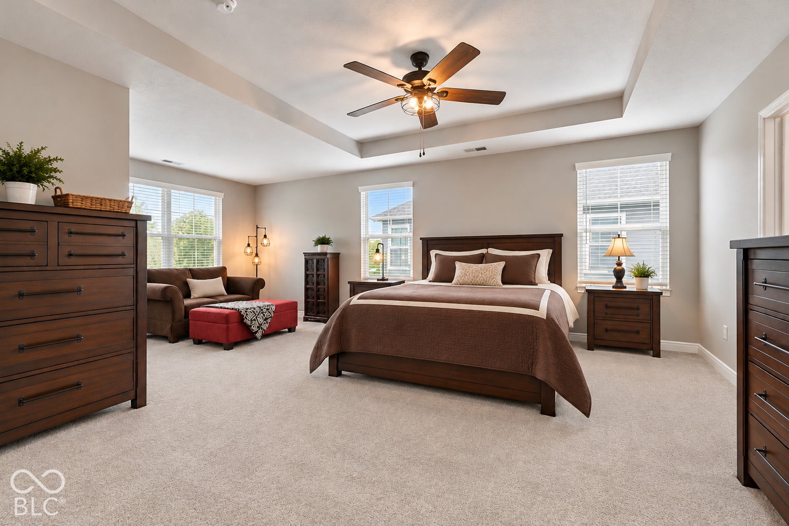 Tray ceiling with a ceiling fan, light gray wall paint, and light-colored carpeting