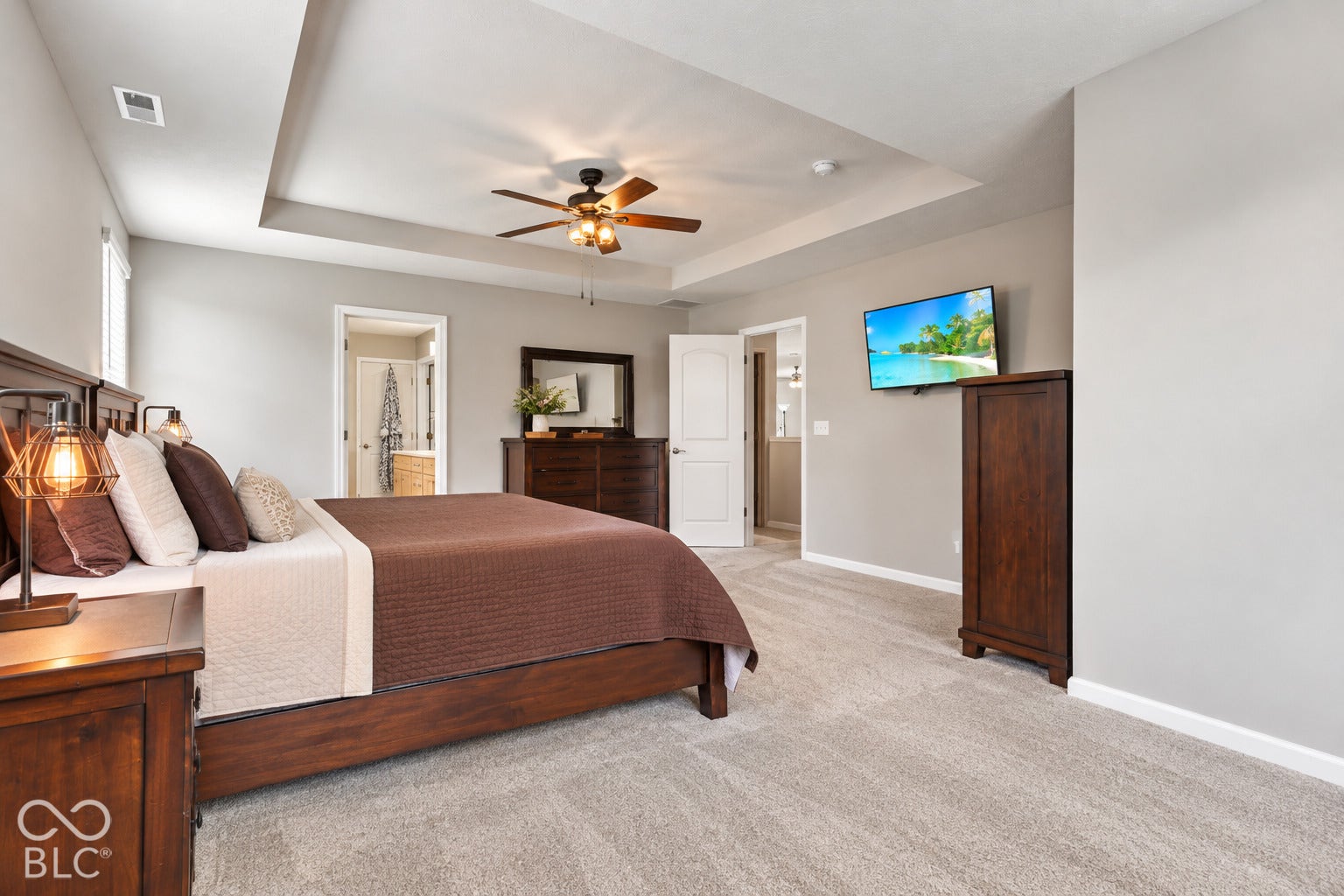 Tray ceiling with a ceiling fan, light gray wall paint, and light gray carpeting