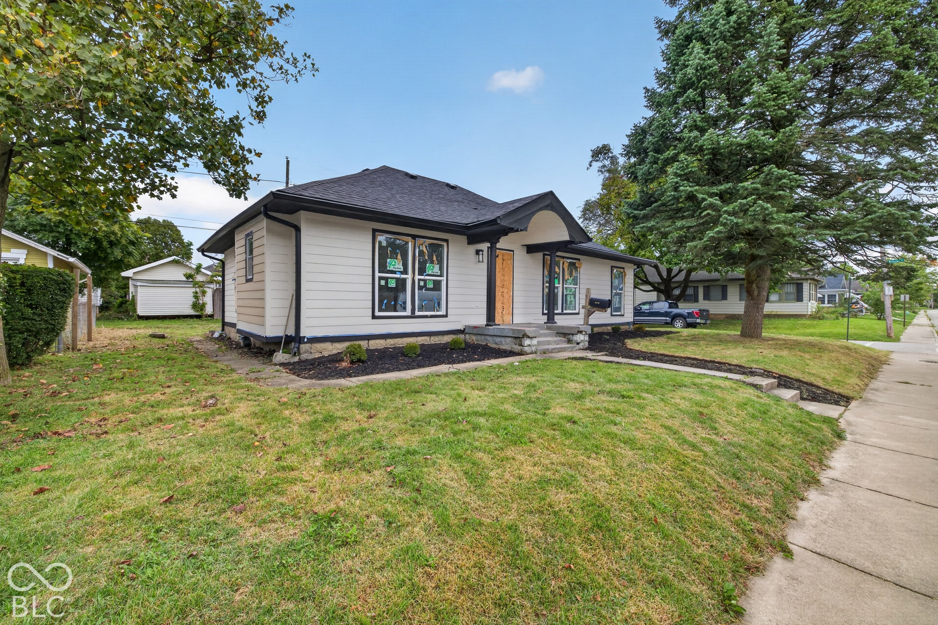 White siding exterior with black trim, dark shingle roof, and a wood-finish front door