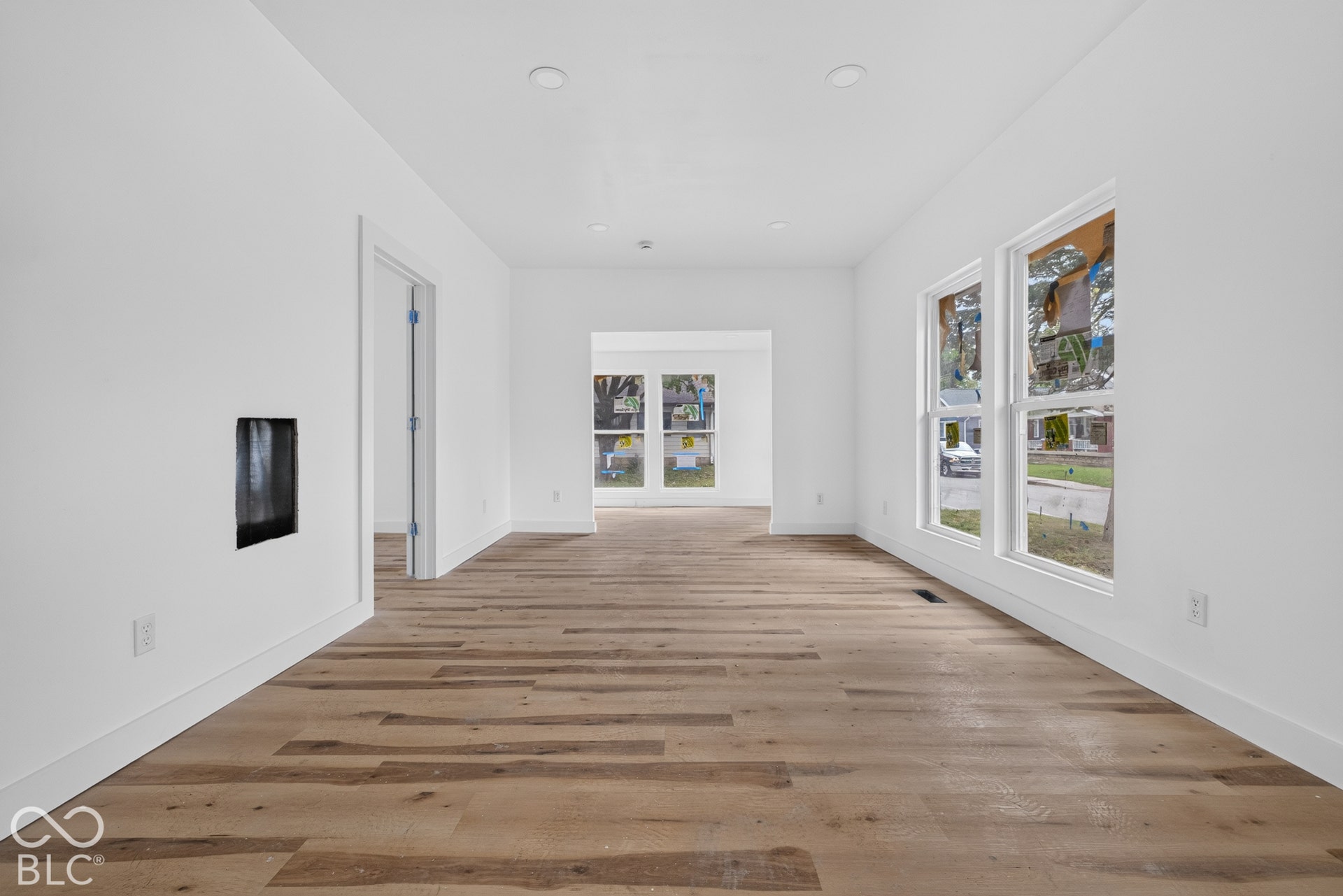Spacious room featuring wood-finish flooring, recessed lighting, multiple windows, and a built-in wall niche