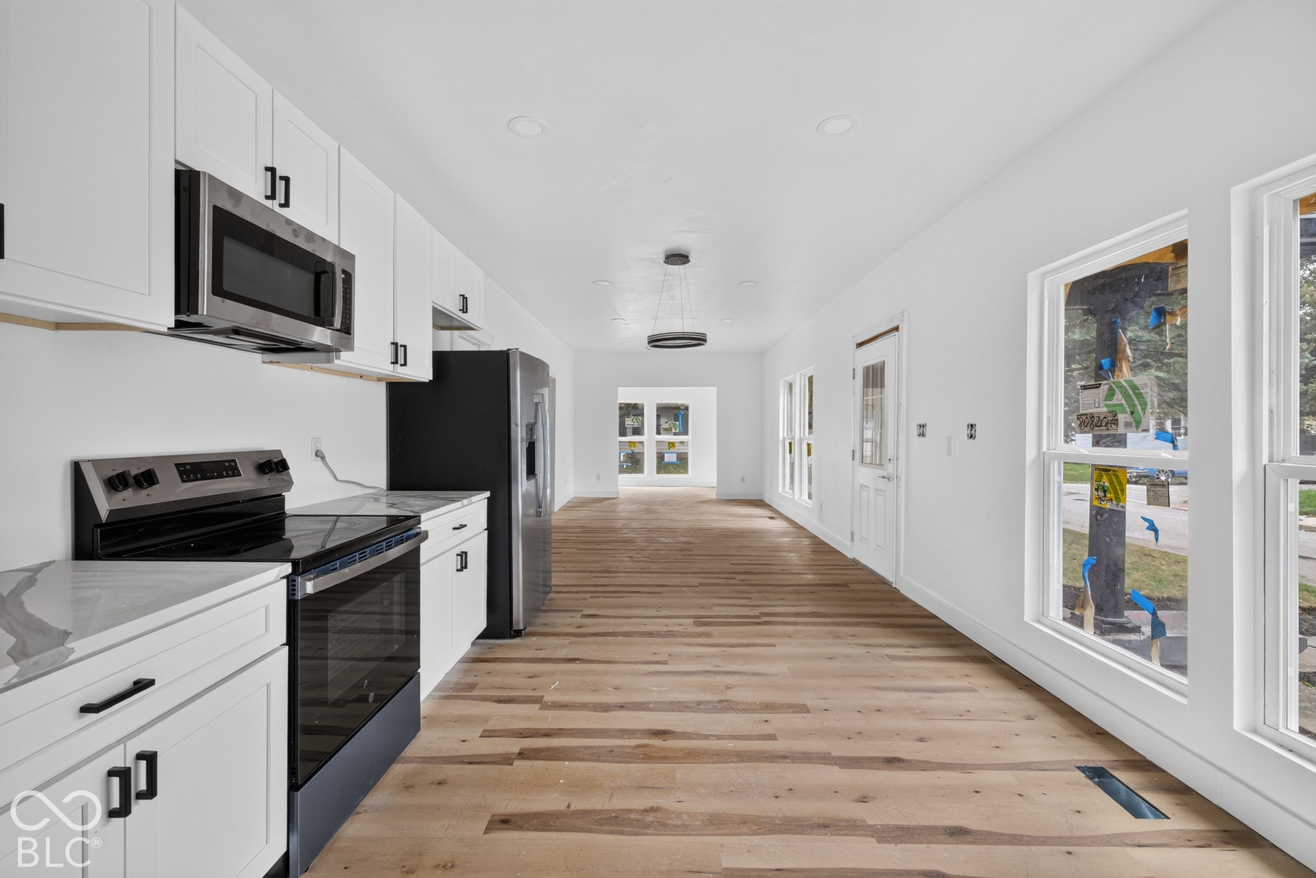 Contemporary kitchen featuring white cabinetry, stainless steel appliances, wood-finish flooring, and white countertops