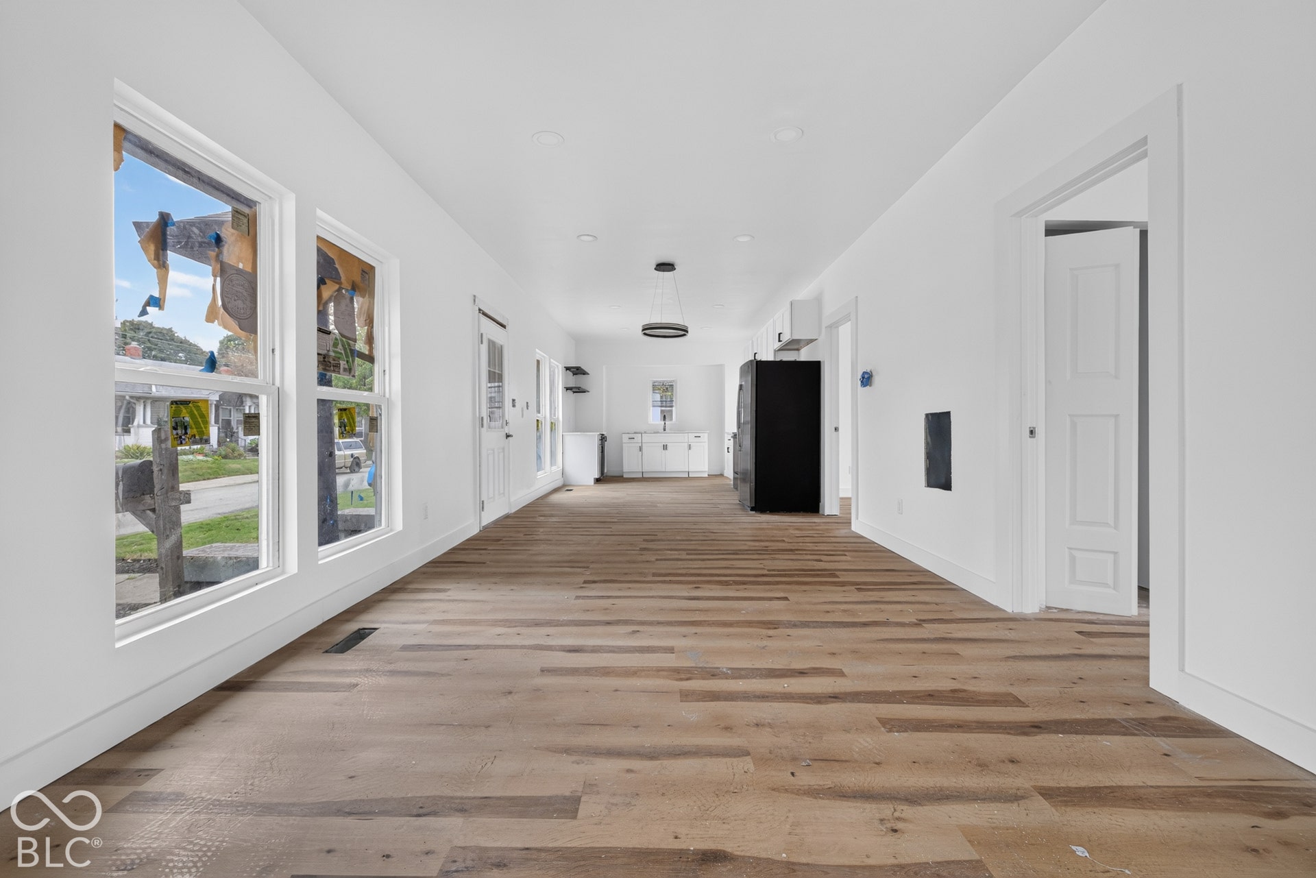 Expansive open-concept room featuring wood-finish flooring and white walls