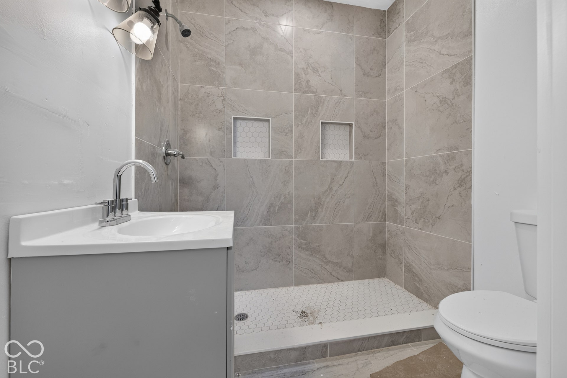 Gray vanity cabinet with integrated sink, chrome faucet, and sconce lighting