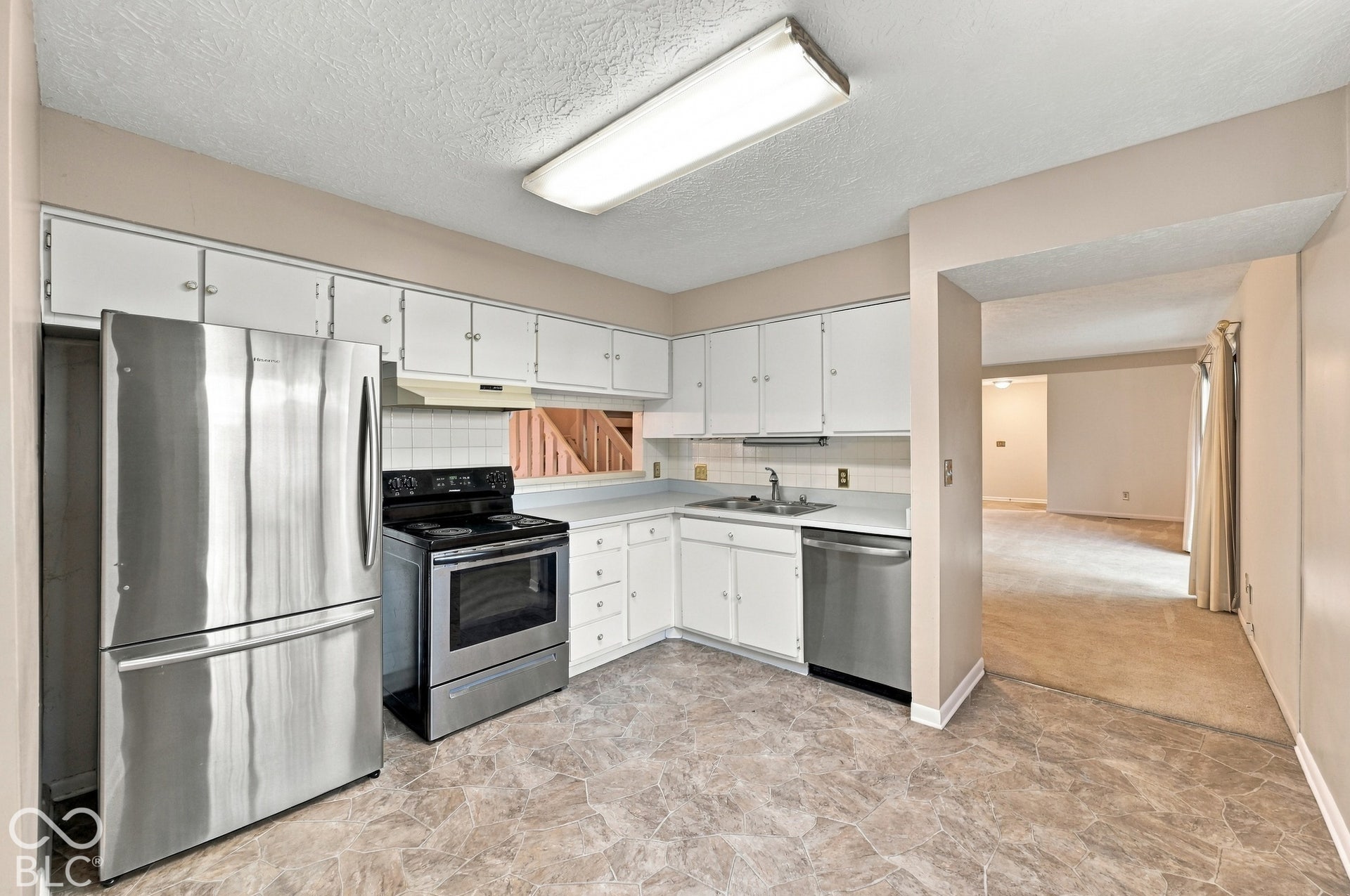 Kitchen featuring stainless steel appliances, white cabinetry, a tile backsplash, and wood-finish flooring
